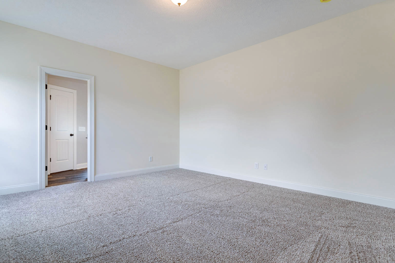 Carpeted room with white walls and a white door featuring black hardware