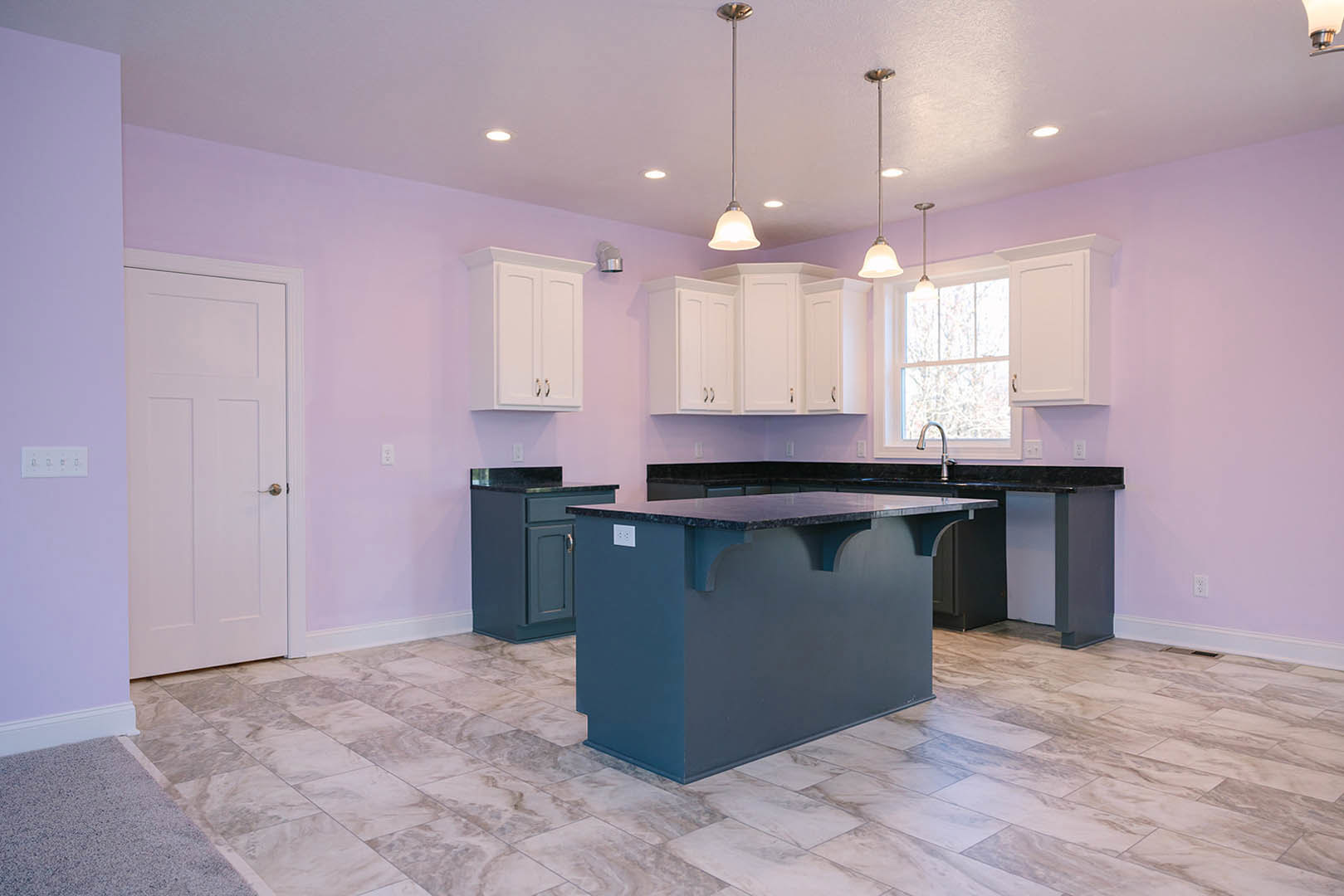 Purple kitchen walls with white cabinets, white door featuring a gold handle, light-colored countertop, tile flooring, row of wall switches, metal pole near cabinetry