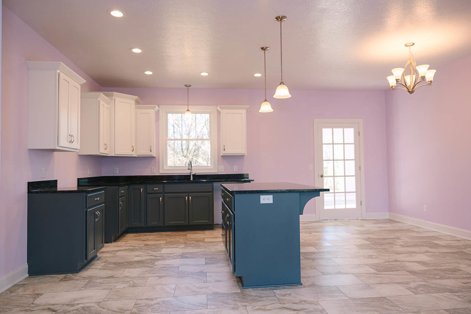 Purple kitchen walls, white cabinets, marble-topped island, glass-paneled white door, window with natural light, light-colored flooring