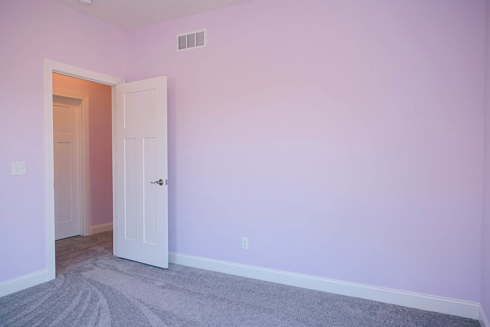 White door open to a room with pink and purple walls, white vent, and beige carpet flooring
