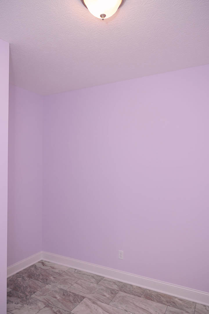 Living room with light purple plaster walls, white ceiling, recessed light fixture, and beige tile flooring