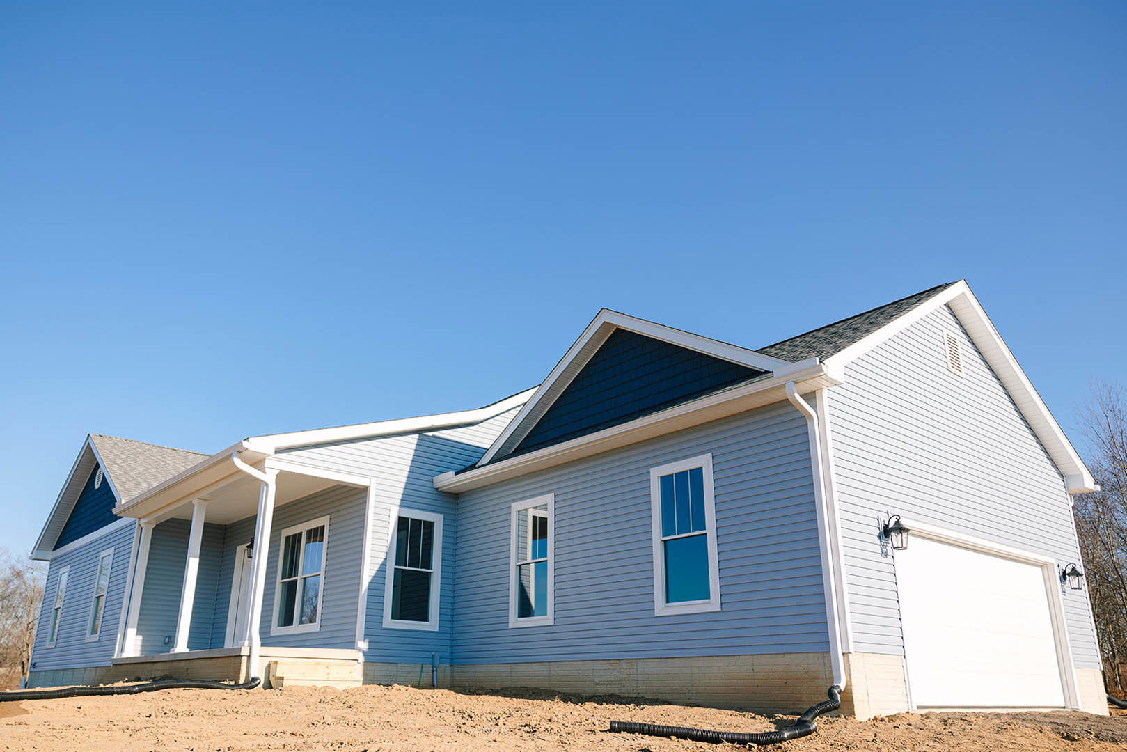 Framed window with white trim set in unfinished siding, blue sky overhead, partially constructed roof visible