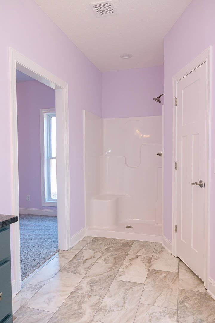Bathroom featuring white tiled shower, marble floor, white door, and window with white frame