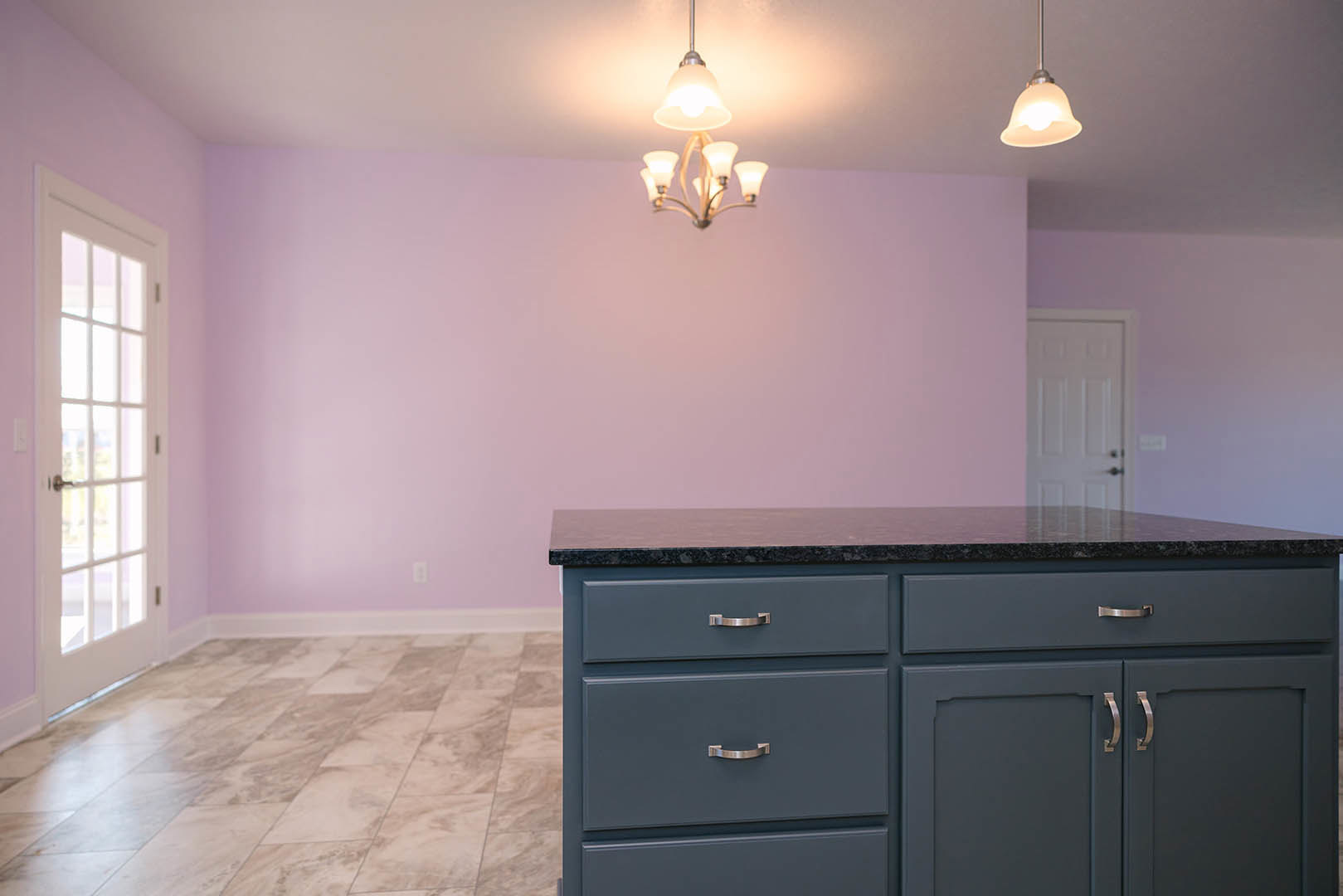 Quartz kitchen island with waterfall edge, pendant lights hanging from ceiling, white cabinetry, hardwood floors, and modern fixtures