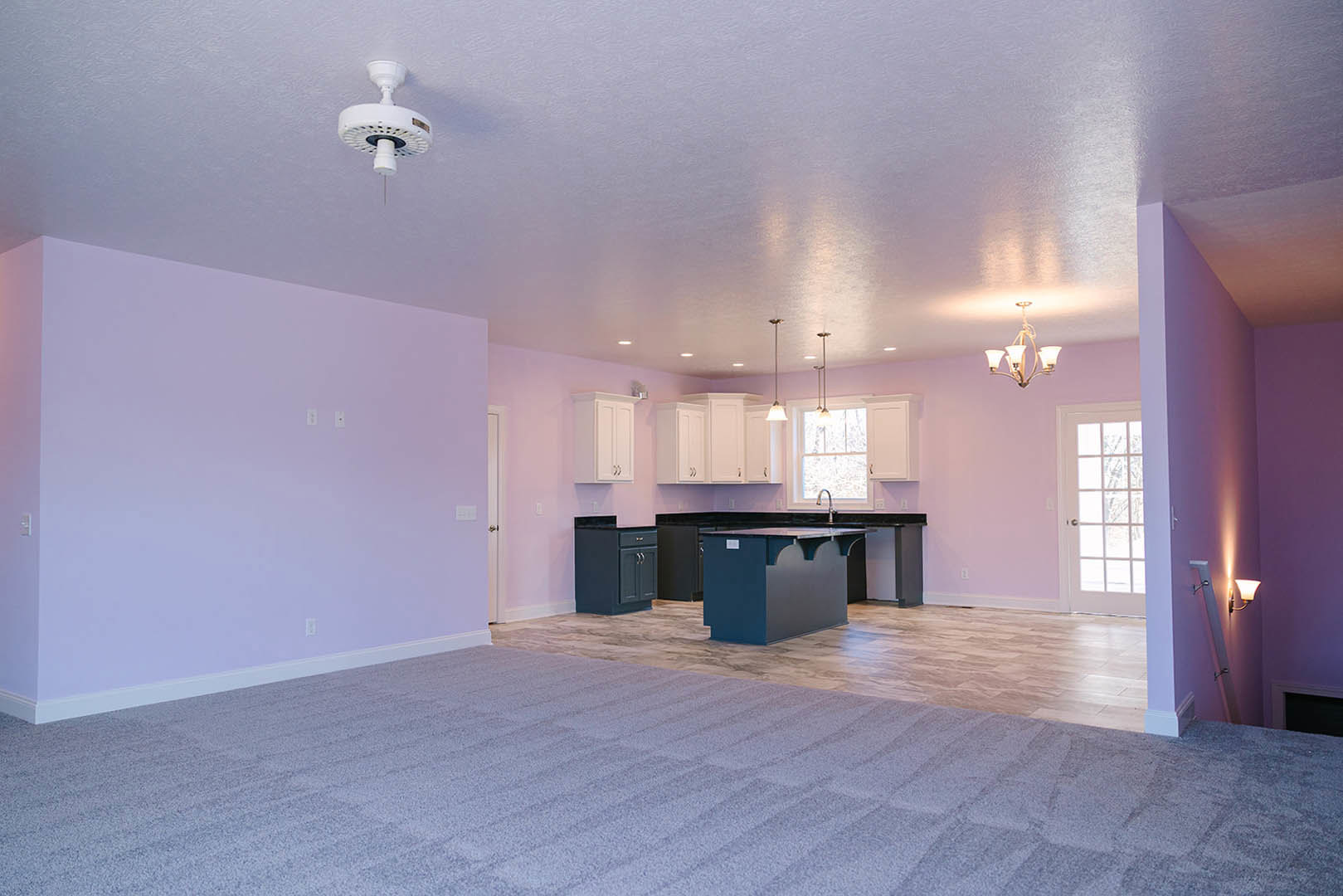 Open kitchen with light purple walls, white ceiling fan, recessed lighting, dark cabinetry, and light flooring