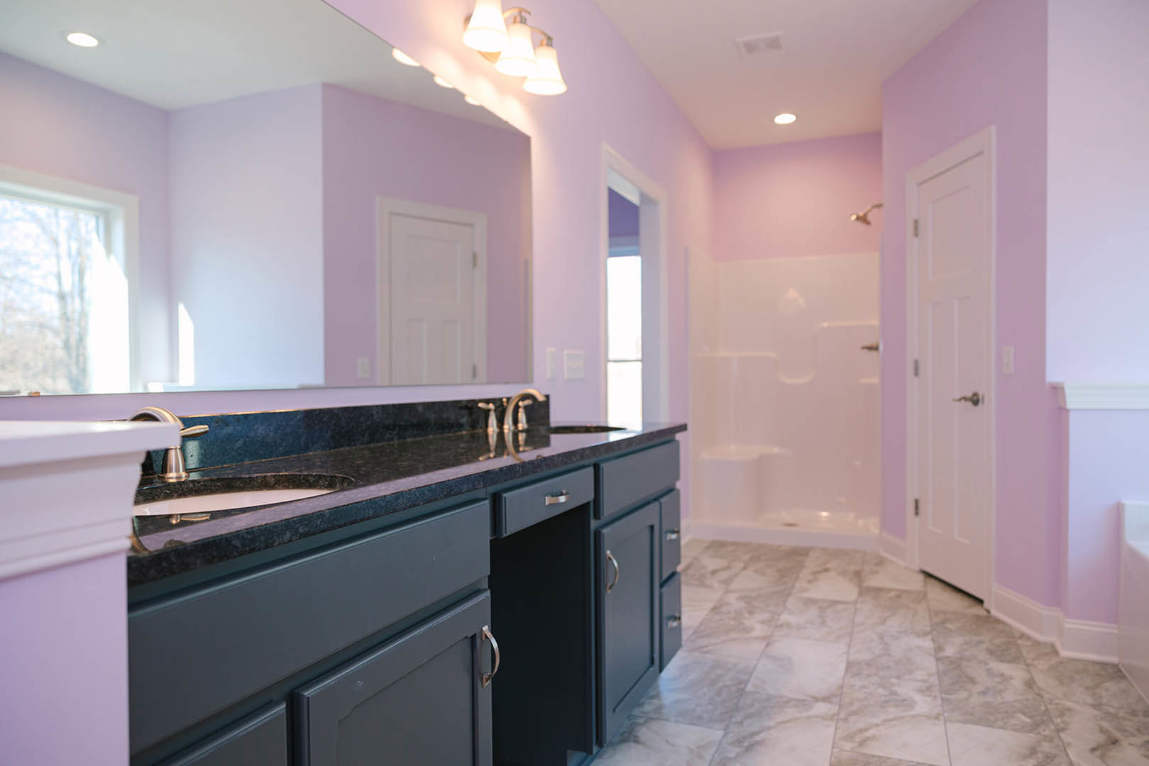 Bathroom with rich purple walls, polished marble floor, white paneled door with silver knob, modern light fixture, and partial view of window.