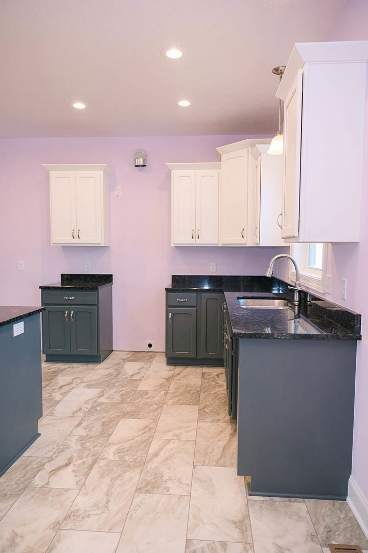 Kitchen with purple walls, white cabinets featuring gold handles, marble tile flooring, and a white countertop near a stainless steel sink