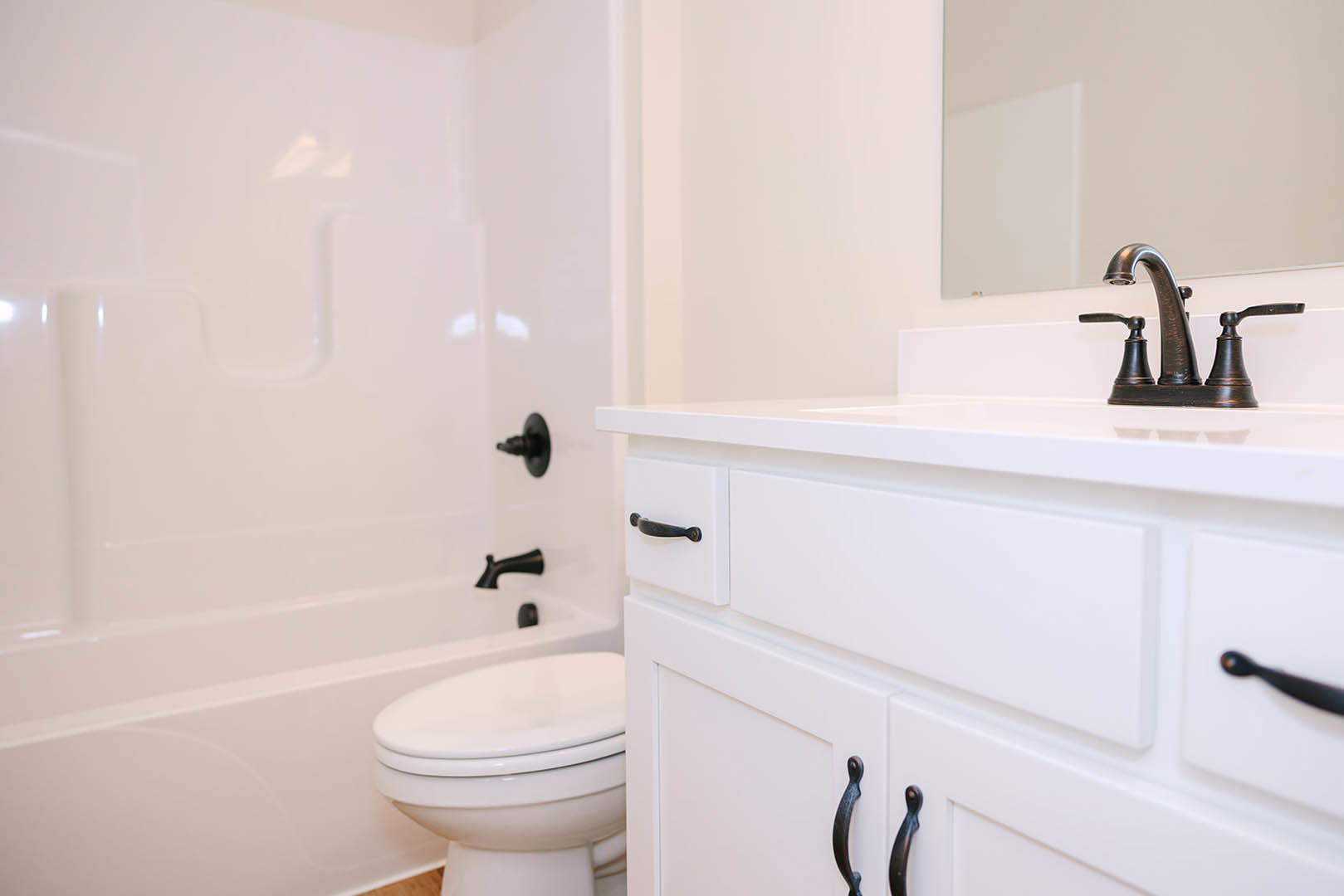 White porcelain sink and toilet in a bathroom with light tile flooring, chrome faucet, and minimalist countertop
