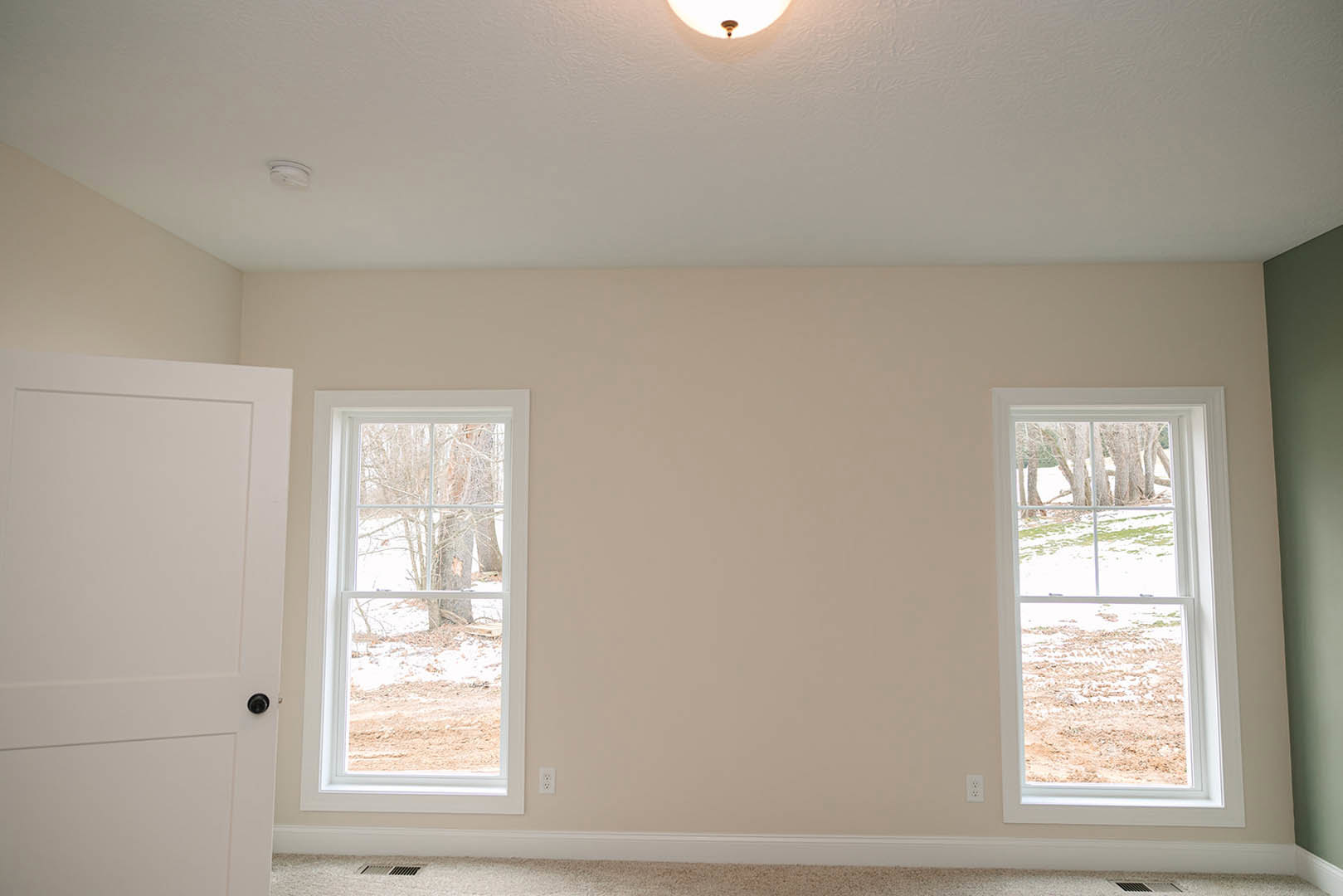 Bright room with two large windows, white plaster walls, decorative molding, and views of snowy trees outside