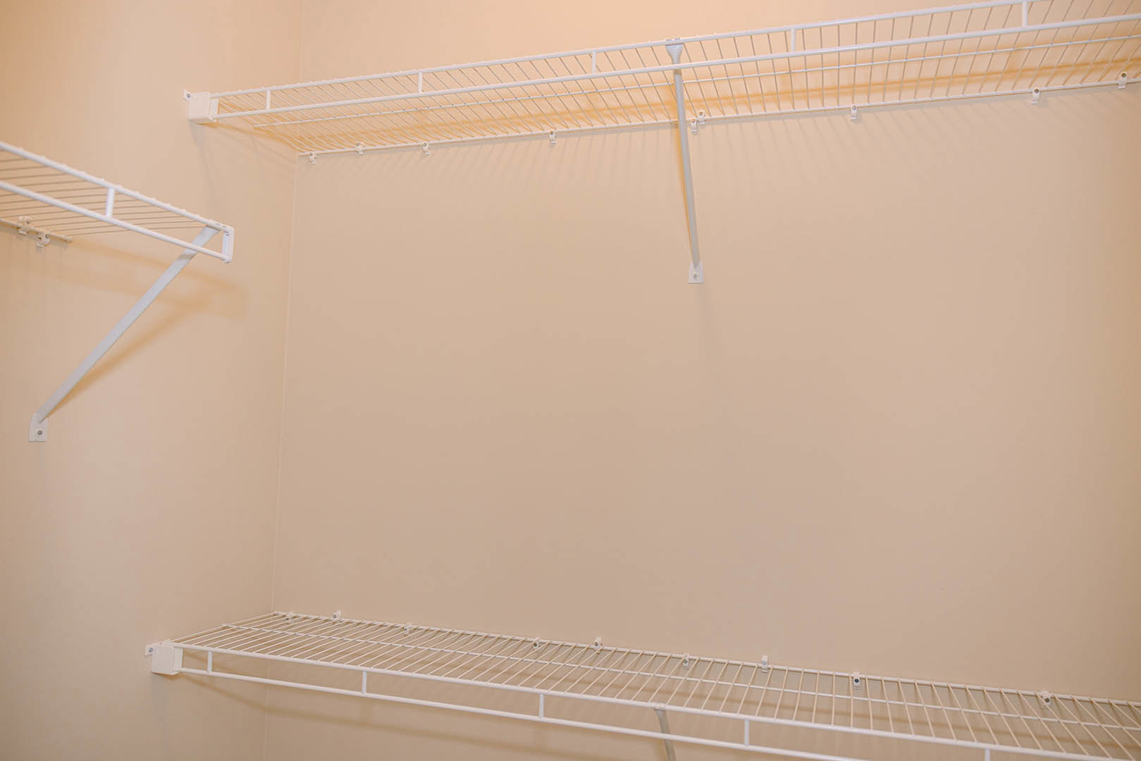 White wire shelving unit with metal rods mounted on a wall in a bright indoor room