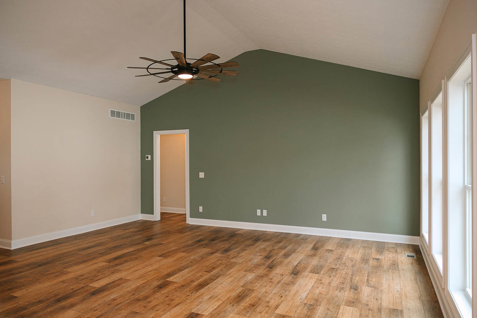Ceiling fan with light fixture, hardwood floor, white plaster walls, window with trim, wall sconce, modern residential interior