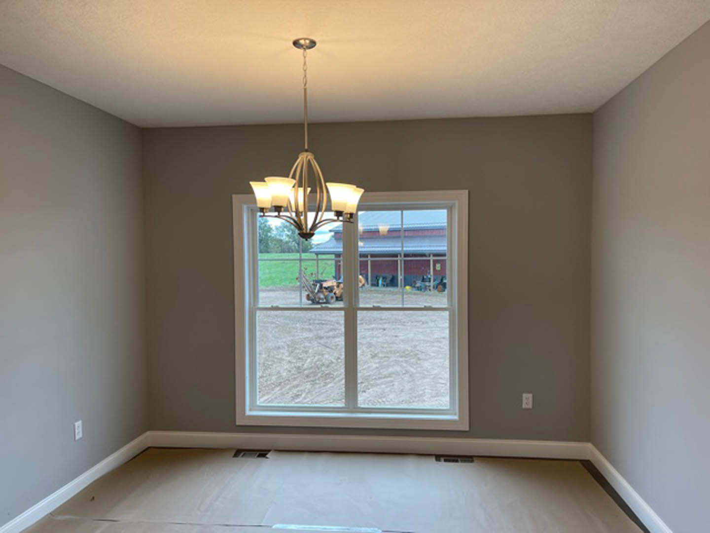 Bright room with white plaster walls, large window with blinds, ornate ceiling molding, and a four-light chandelier hanging from the ceiling.