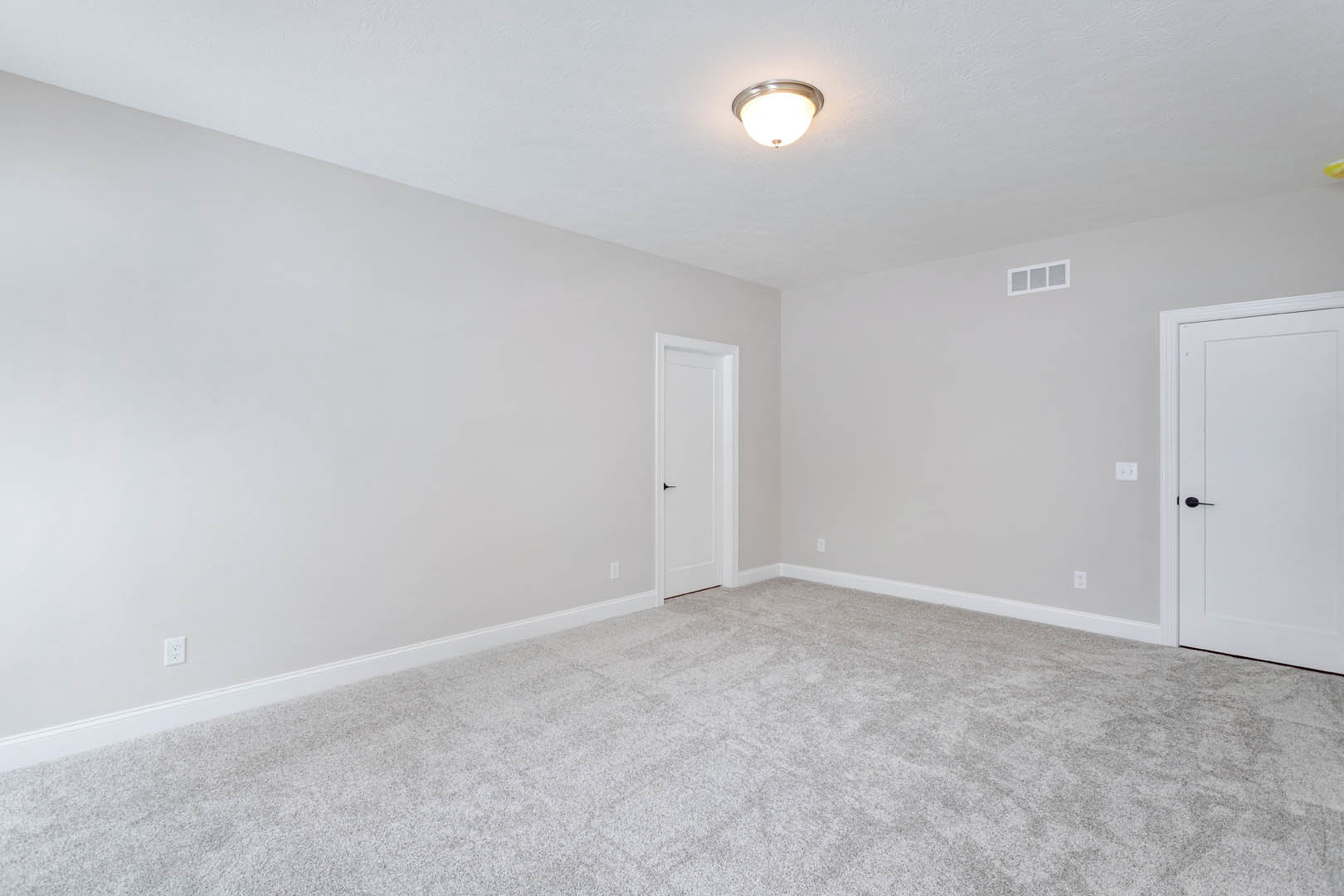 Carpeted room with white door featuring black handle, white square window with trim, light fixture on ceiling, pale walls