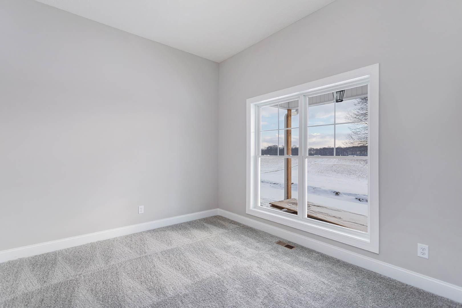 Carpeted bedroom with large window overlooking snowy landscape, white plaster walls, wood trim, and ceiling molding