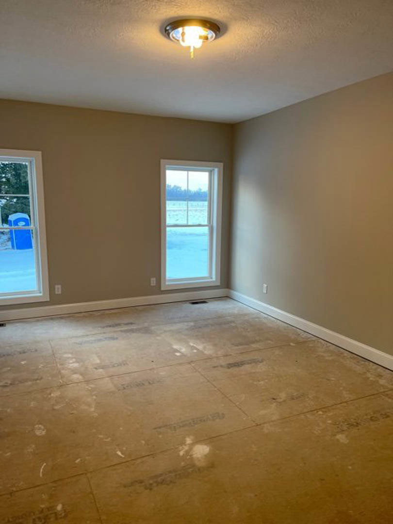 Tile flooring in a bright room with plaster walls, large windows overlooking the ocean, ceiling light fixture, and a blue container visible outside