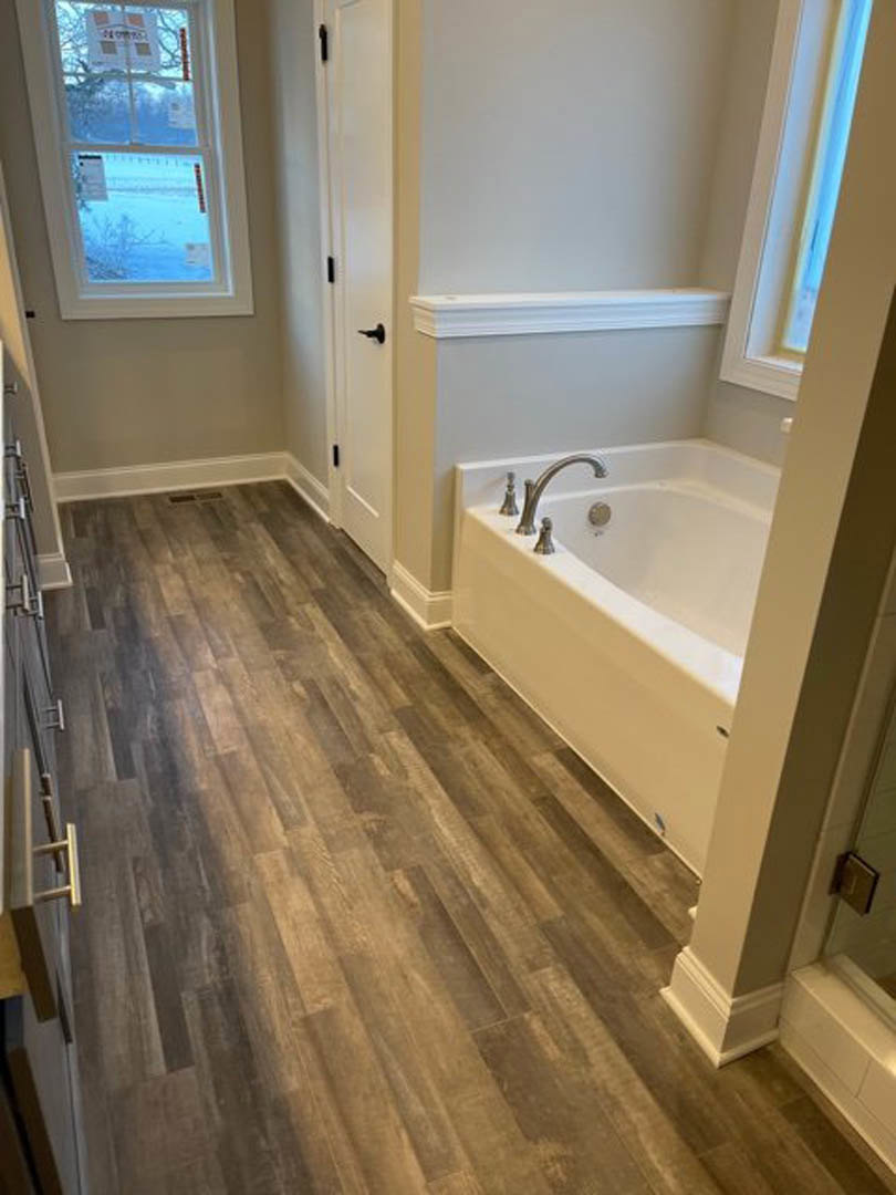 Bathroom with wood flooring, freestanding bathtub, chrome faucet, large window overlooking snowy landscape