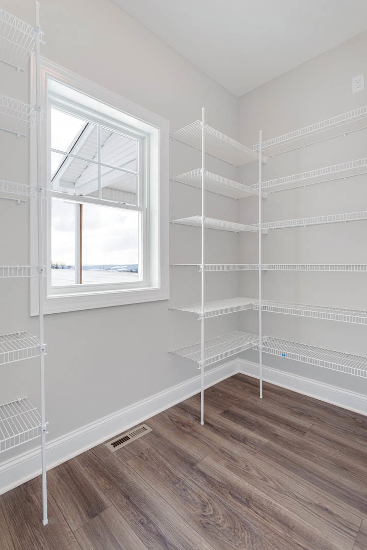 White closet with wire shelving, wood floor vent, and window with plaster walls and ceiling