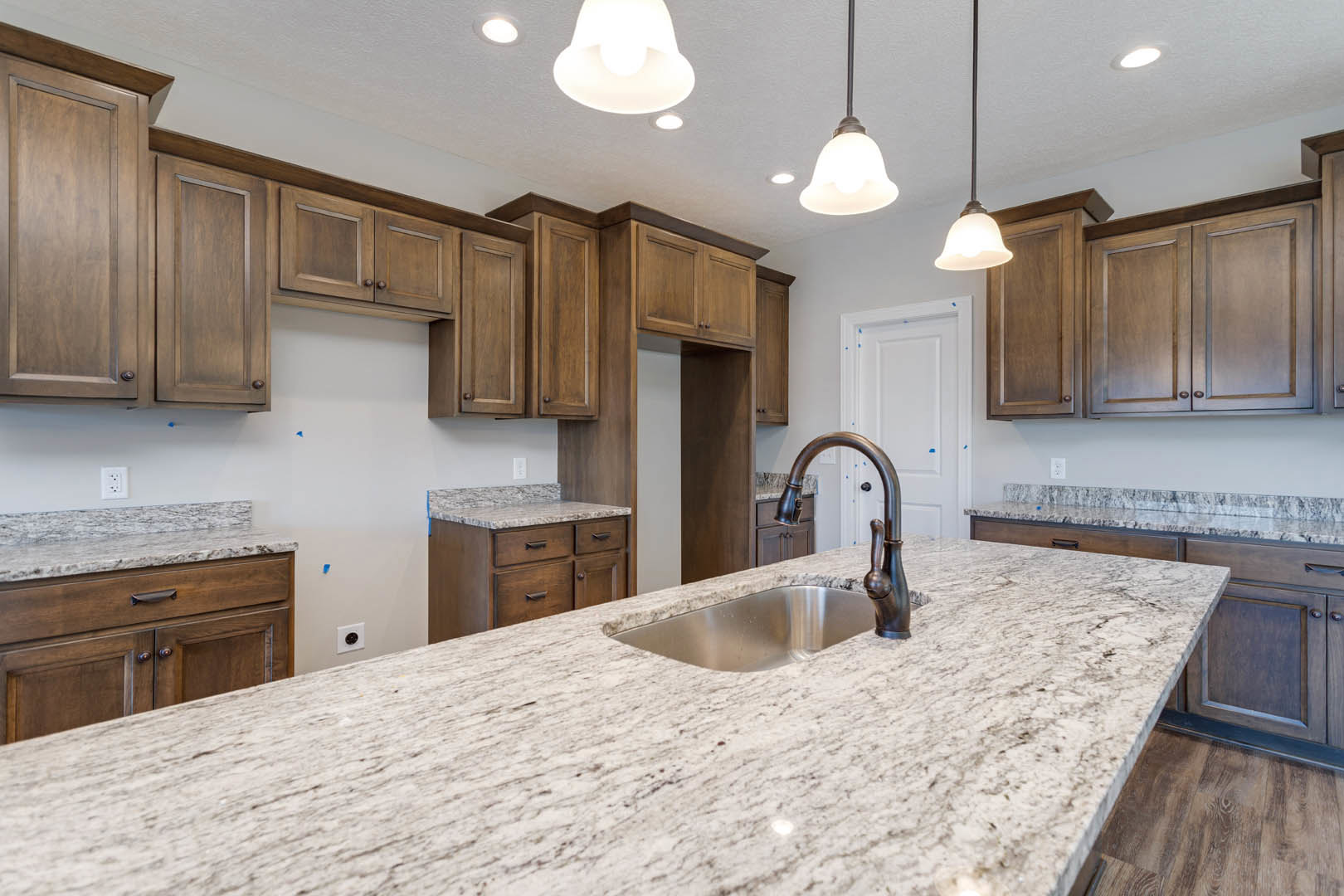White quartz countertop with stainless steel undermount sink, brushed nickel faucet, and shaker-style wood cabinets in a modern kitchen