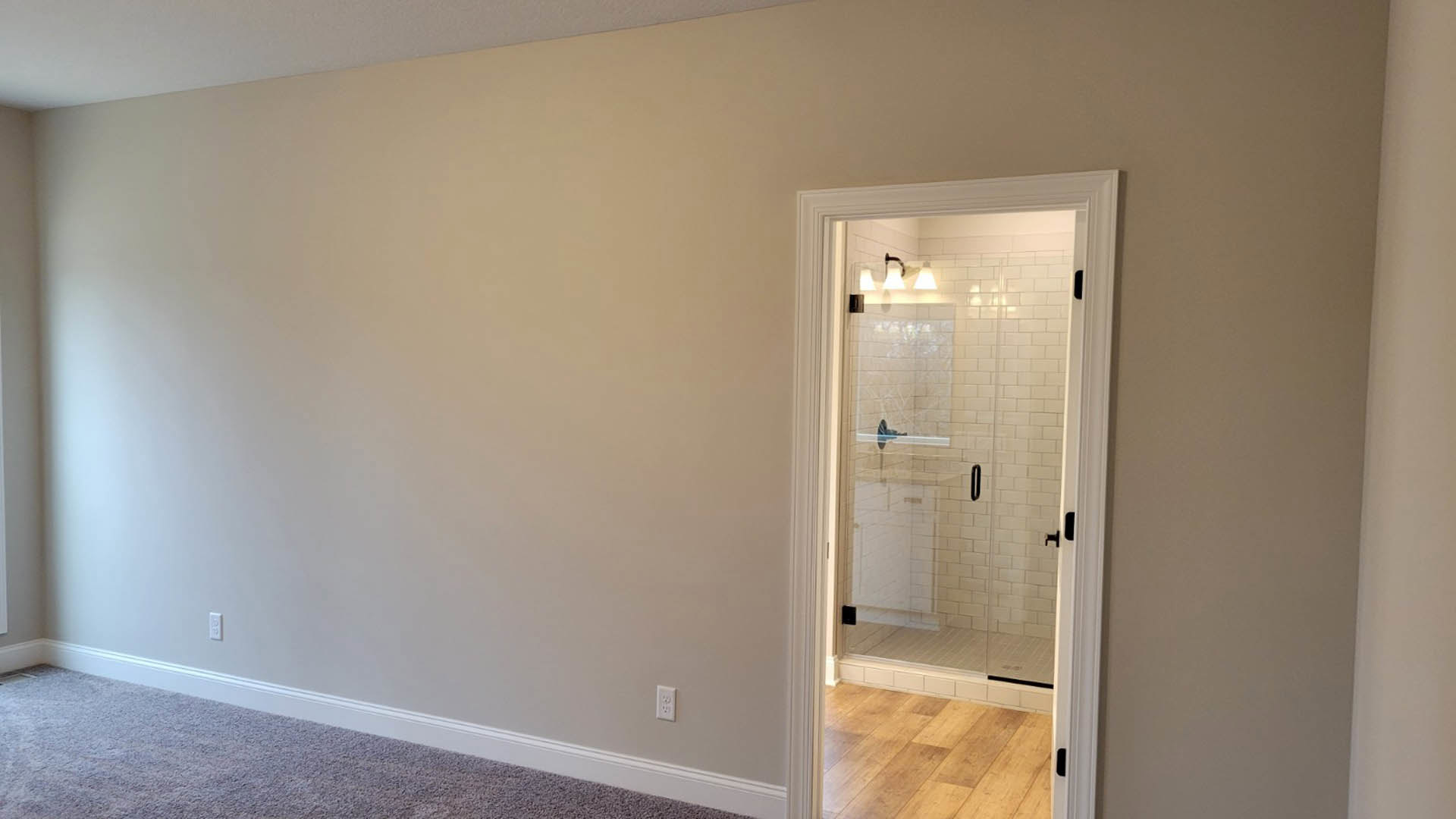 Bathroom featuring a glass shower door, white tile floor, white walls, and ceiling with adjacent wood flooring