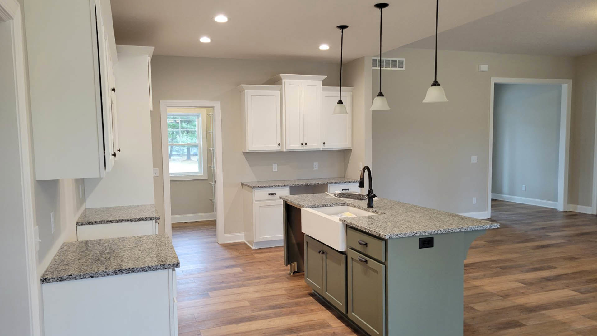 Kitchen with white shaker cabinets, speckled granite countertops, stainless steel sink, tile backsplash, and window overlooking trees