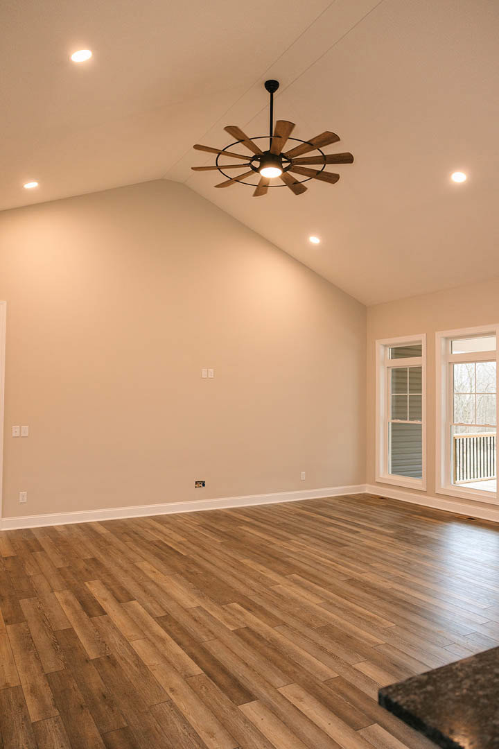 Hardwood floor with white trim, ceiling fan with light, white-framed window overlooking balcony, neutral walls, partial view of countertop
