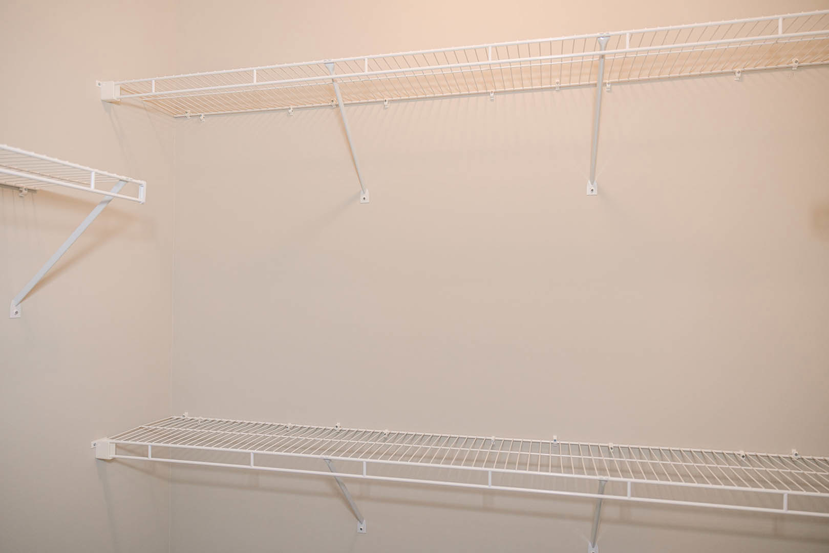 White wire shelving mounted on a white wall in a simple indoor room