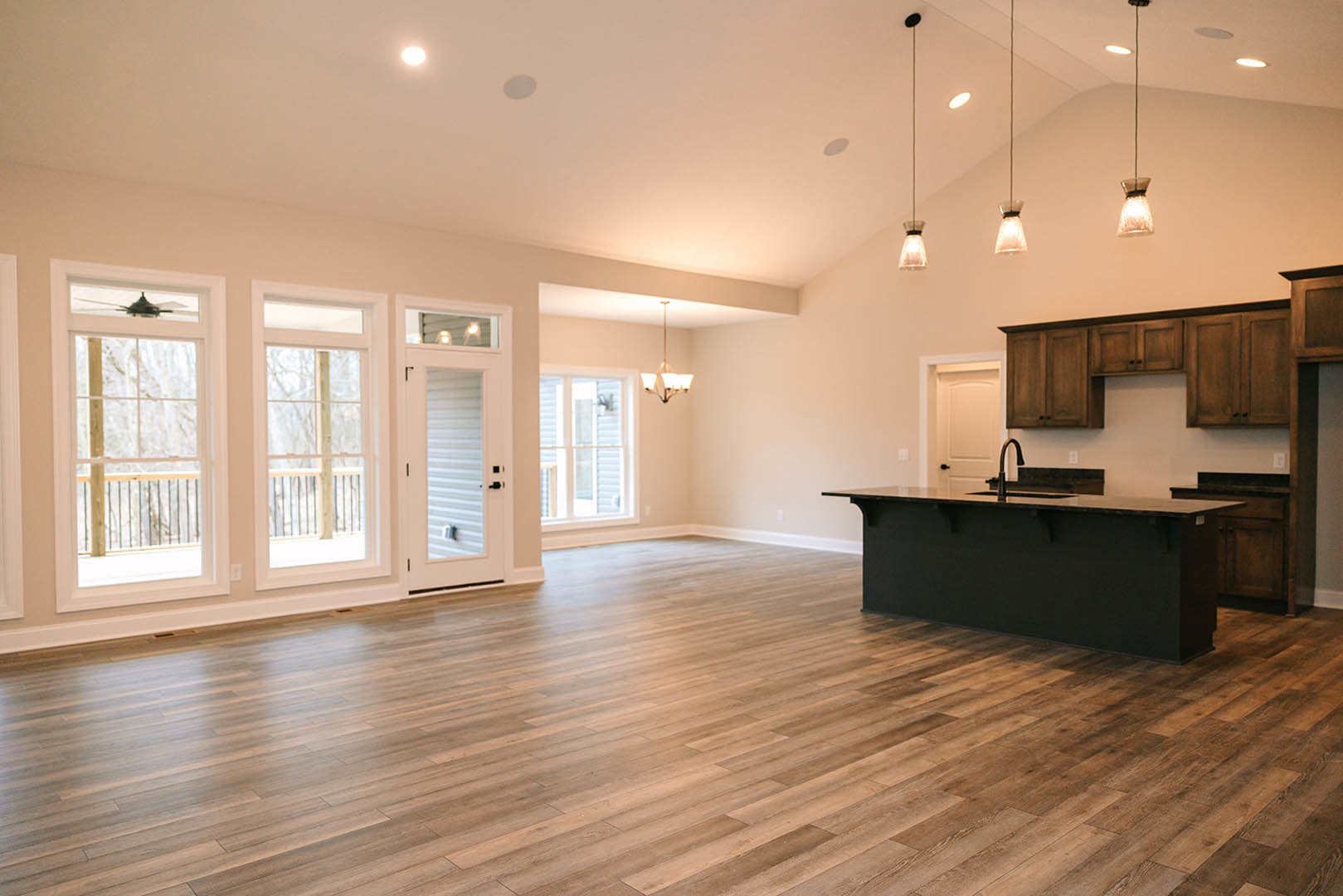 Spacious kitchen with black countertop island, hardwood floors, white cabinetry, large windows framing snowy mountain views, and a white door with glass panel