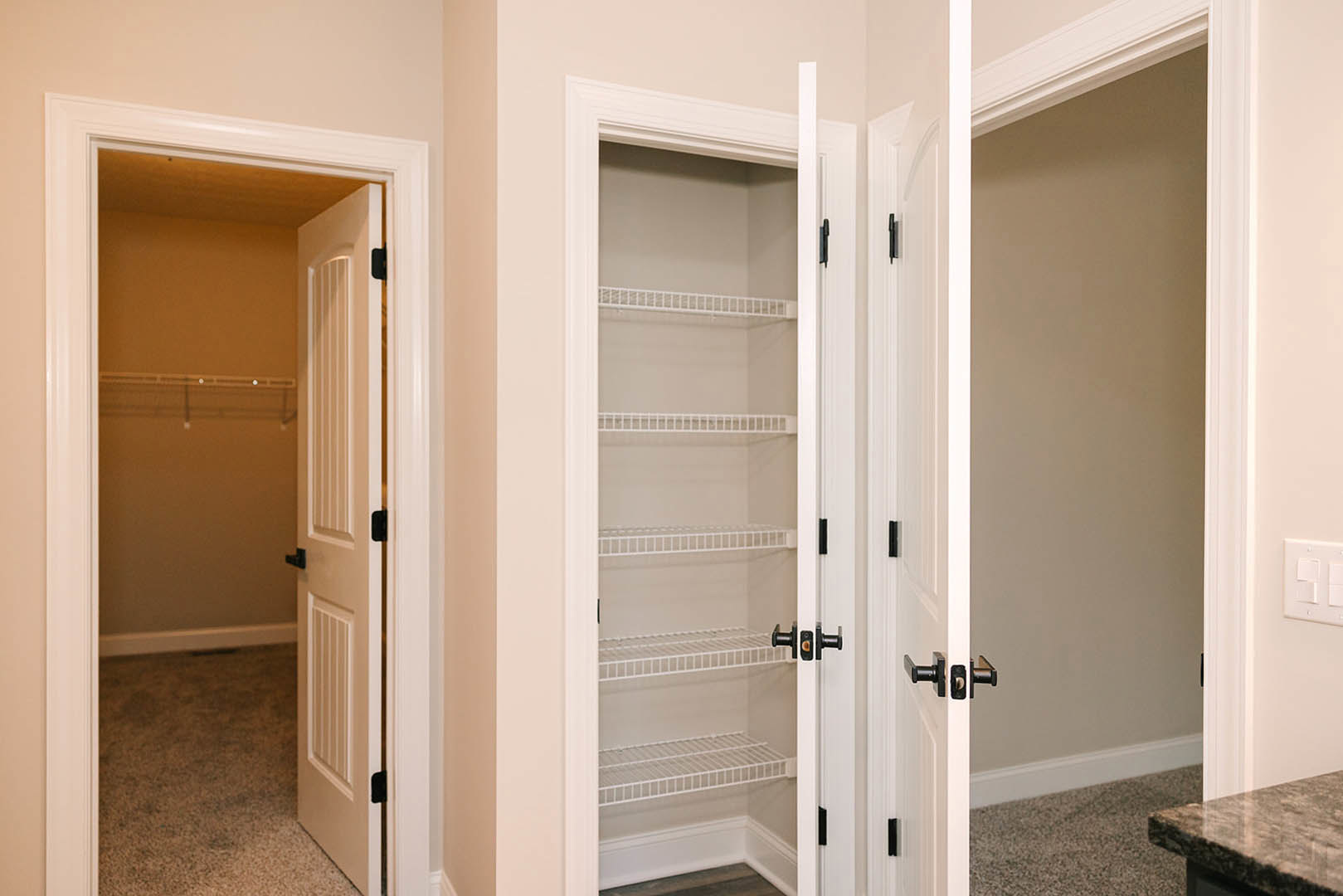White closet with built-in shelves, white door, and light wood flooring in a residential room