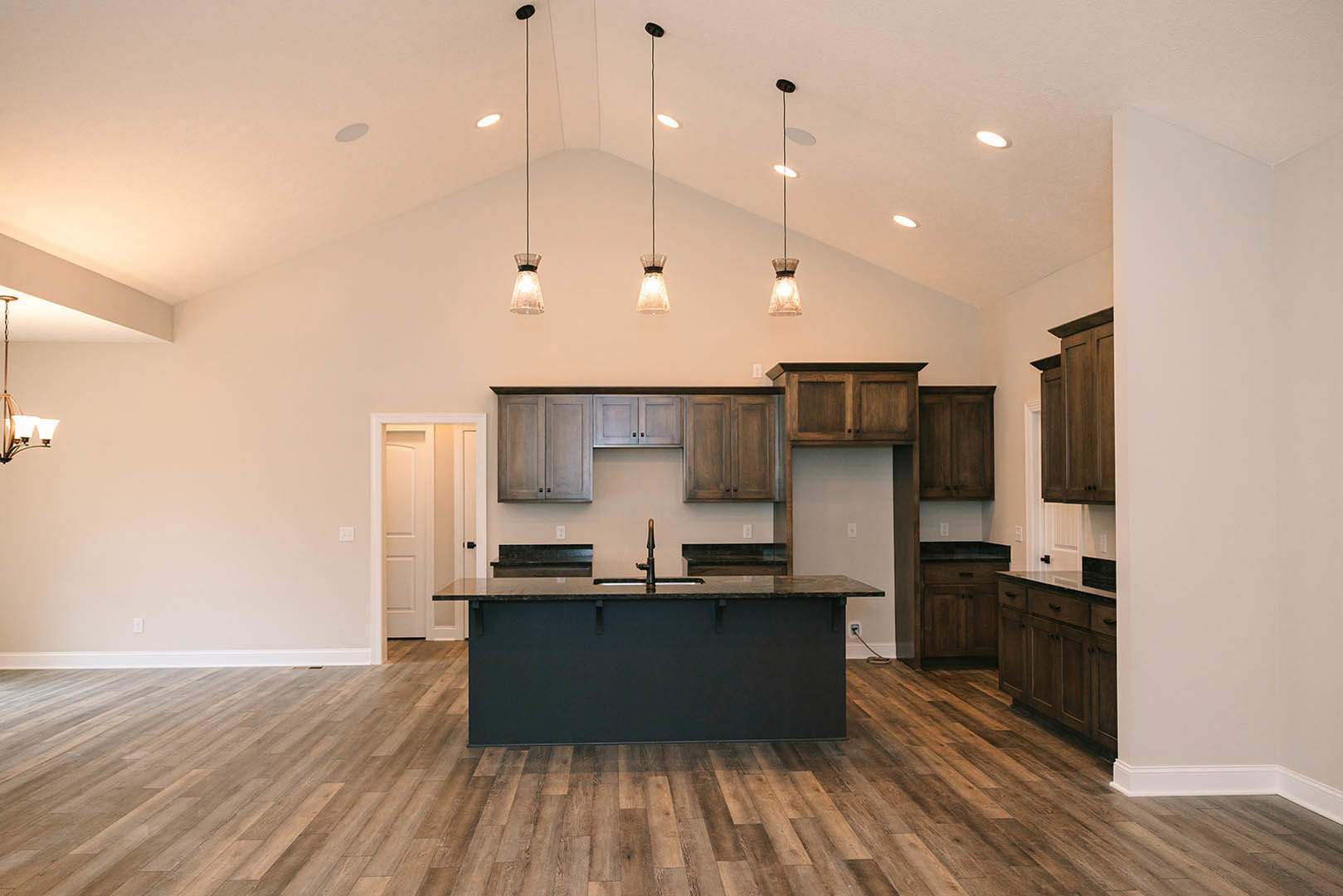 Kitchen featuring a matte black island with integrated sink, light hardwood floors, minimalist cabinetry, and white walls with black accents