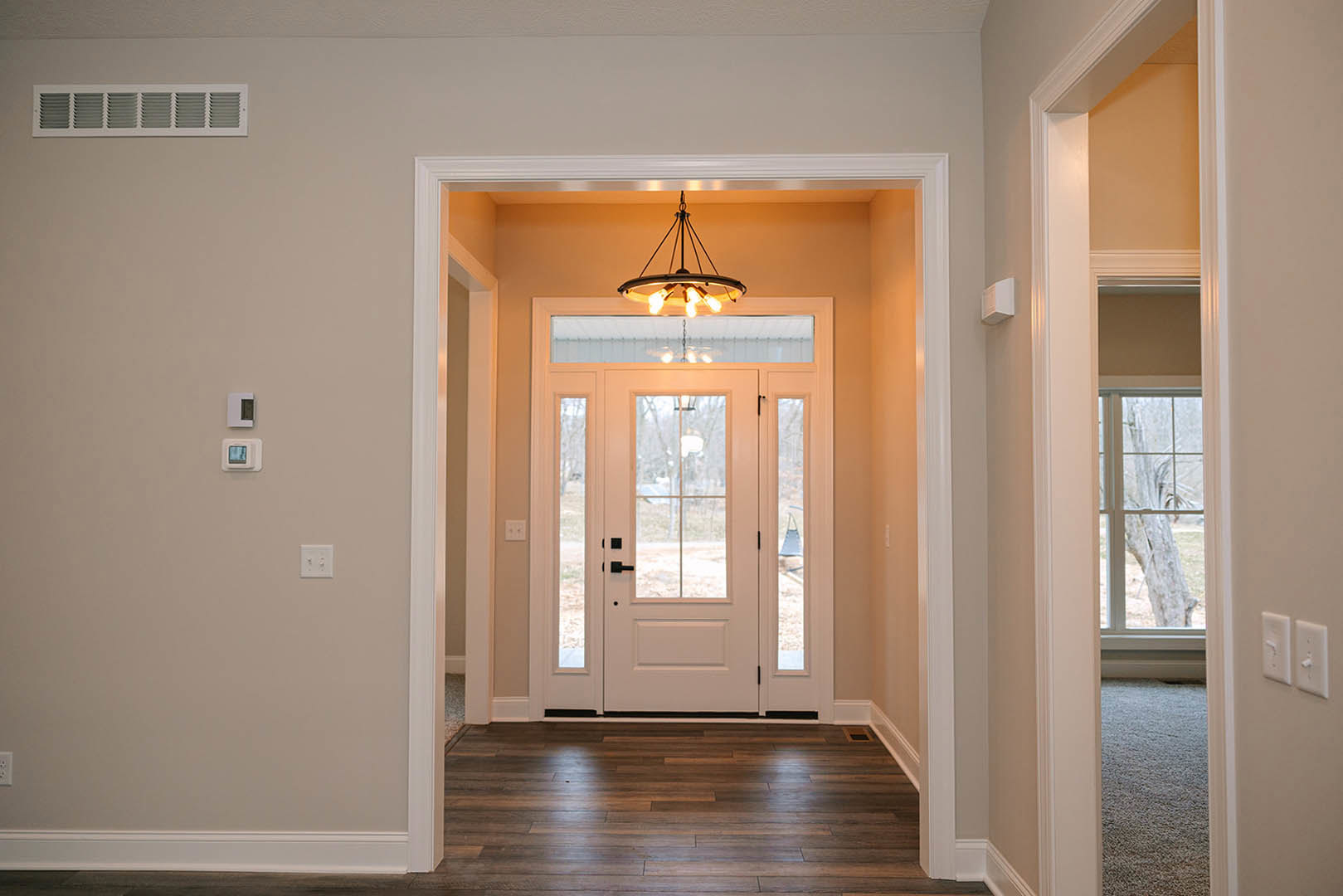 Hallway with wood flooring, white door featuring glass panels, circular ceiling light fixture, white wall box, and decorative molding