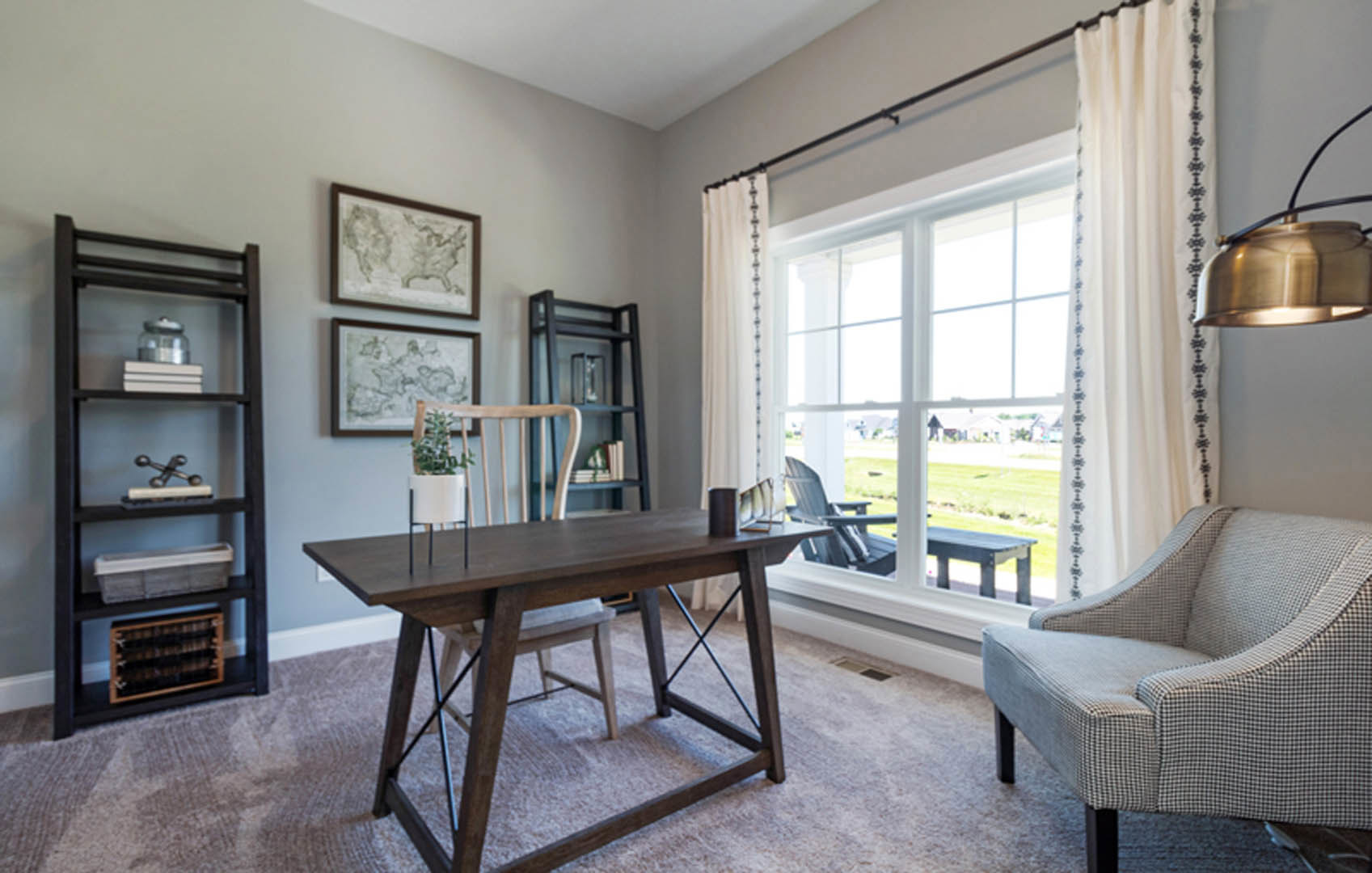 Dining room with wooden table, upholstered chairs, bookshelf filled with books and decor, neutral walls, large window, and hardwood flooring