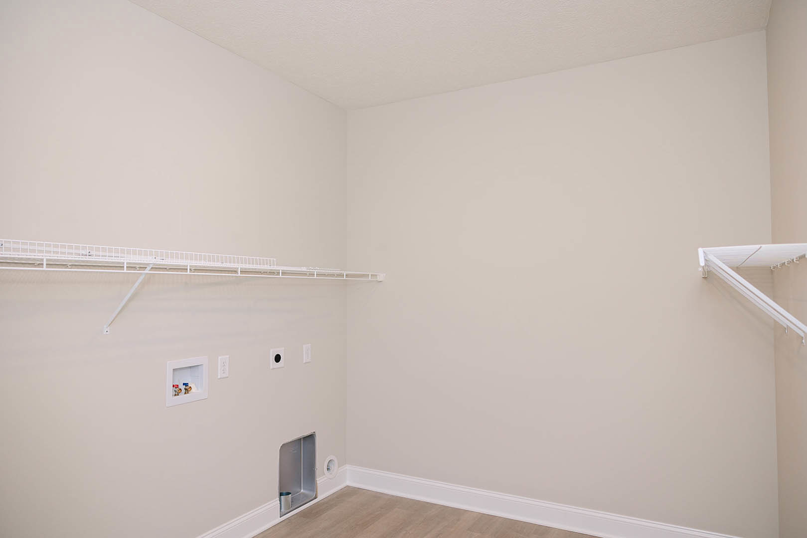 White plaster wall featuring a built-in shelf, square recessed opening, and white ceiling corner.