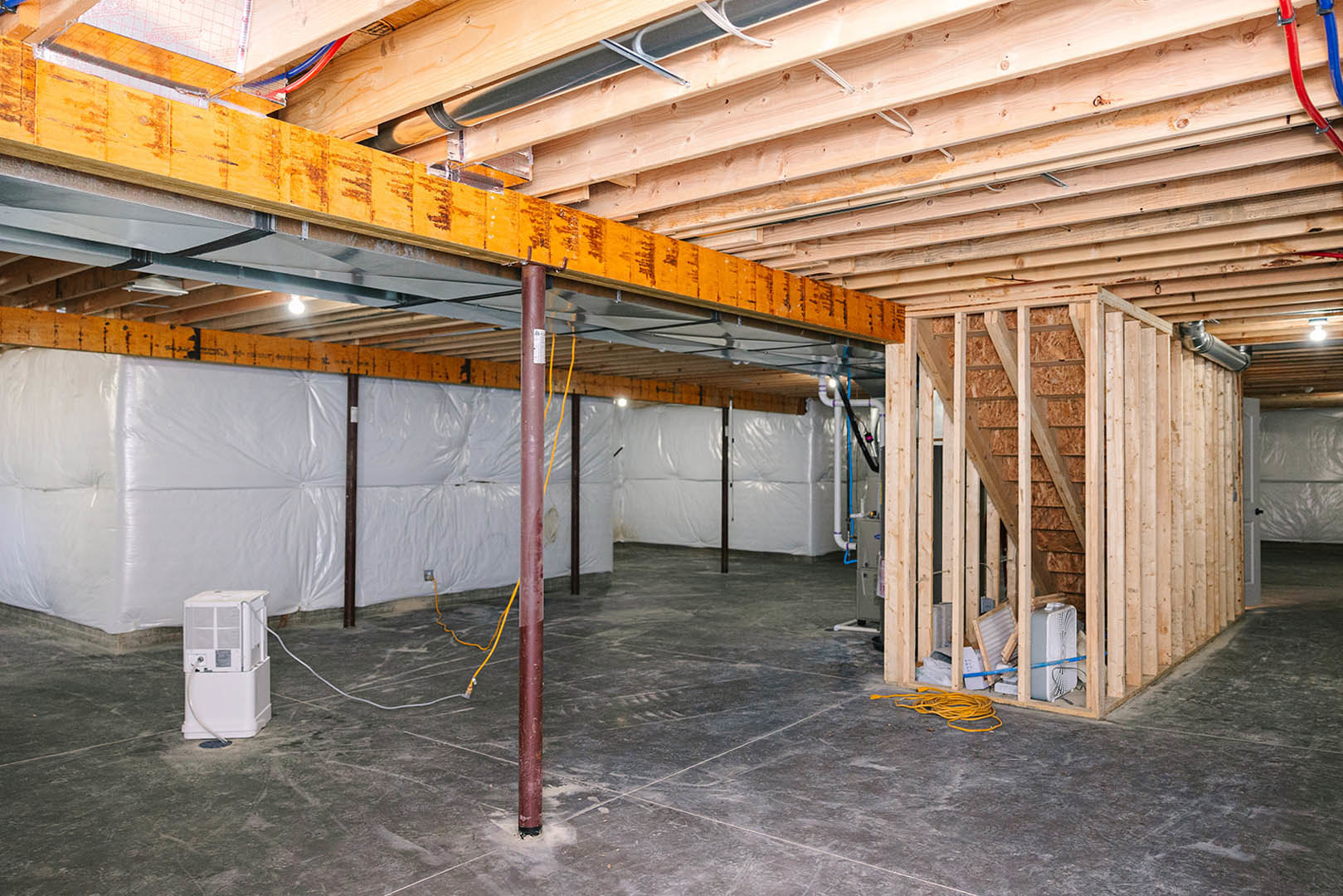 Exposed metal beam crossing a white ceiling in a modern room, with visible wall insulation and a mounted white HVAC unit.