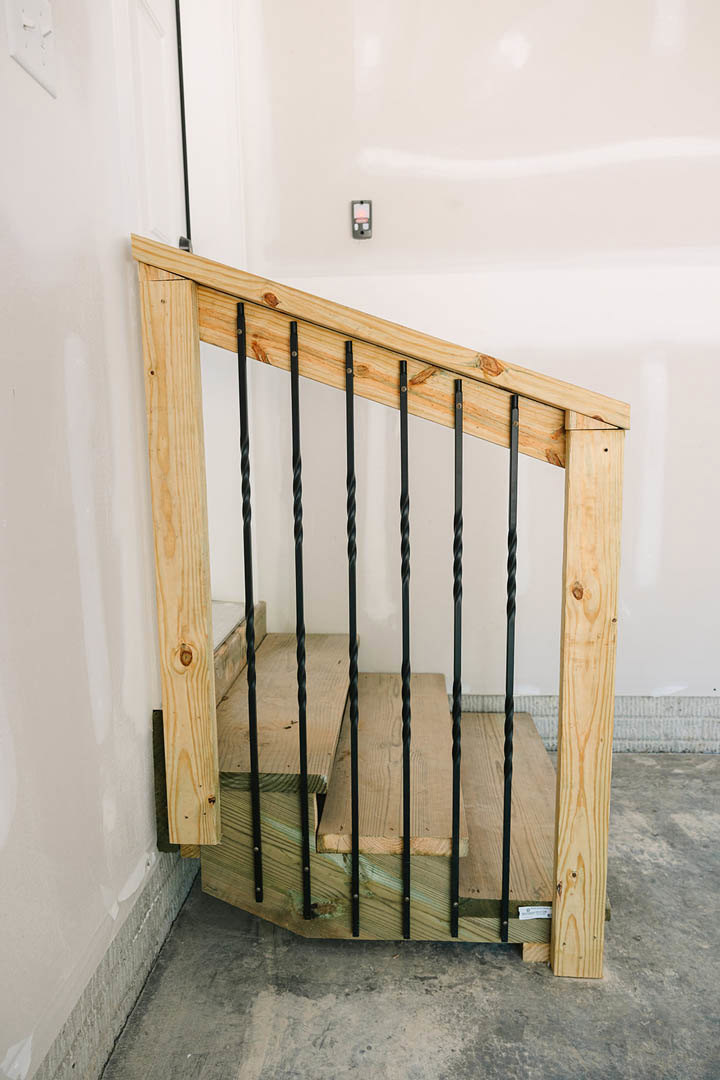 Wooden staircase with sleek metal railings, white walls, and close-up view of wood planks and iron rods