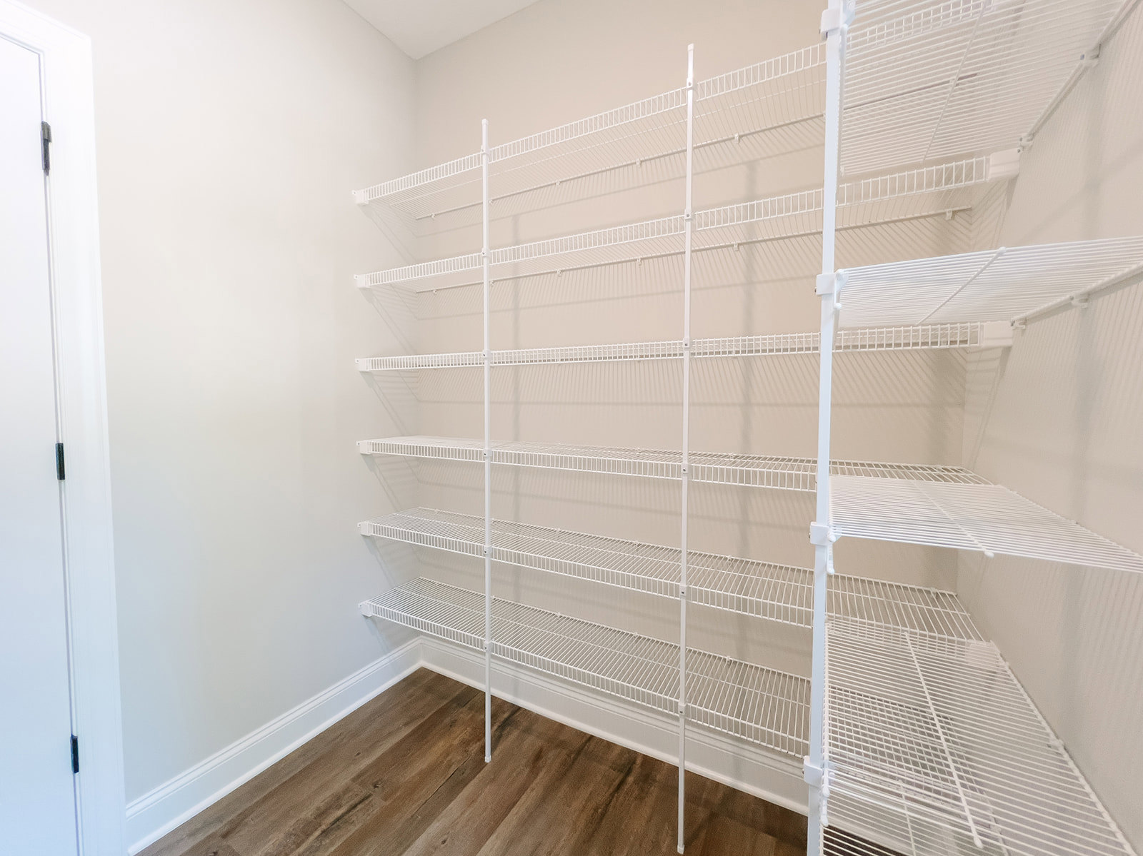 White built-in shelves against a light-colored wall, wood flooring, and minimalist decor in a residential room.