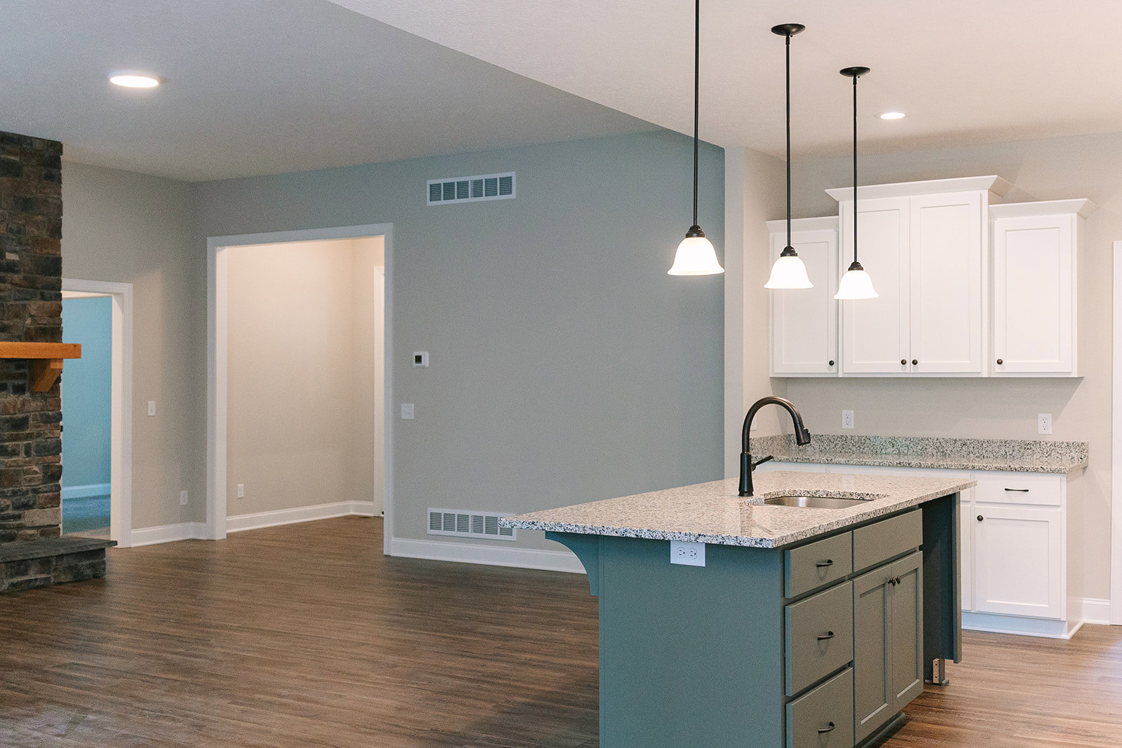 Open kitchen with wood plank flooring, white cabinetry, central island featuring sink and drawers, stainless steel faucet, overhead recessed lighting, window with vent, and black
