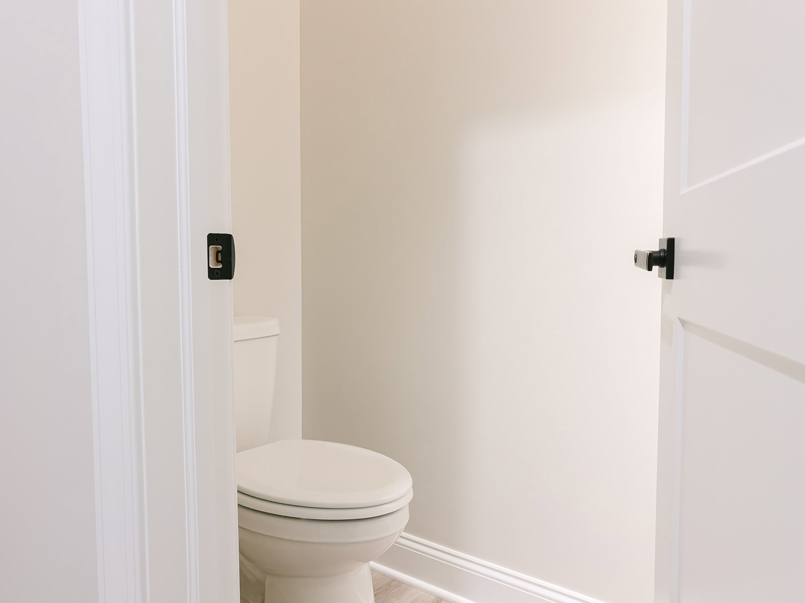 White porcelain toilet with closed seat lid set against light tiled bathroom wall
