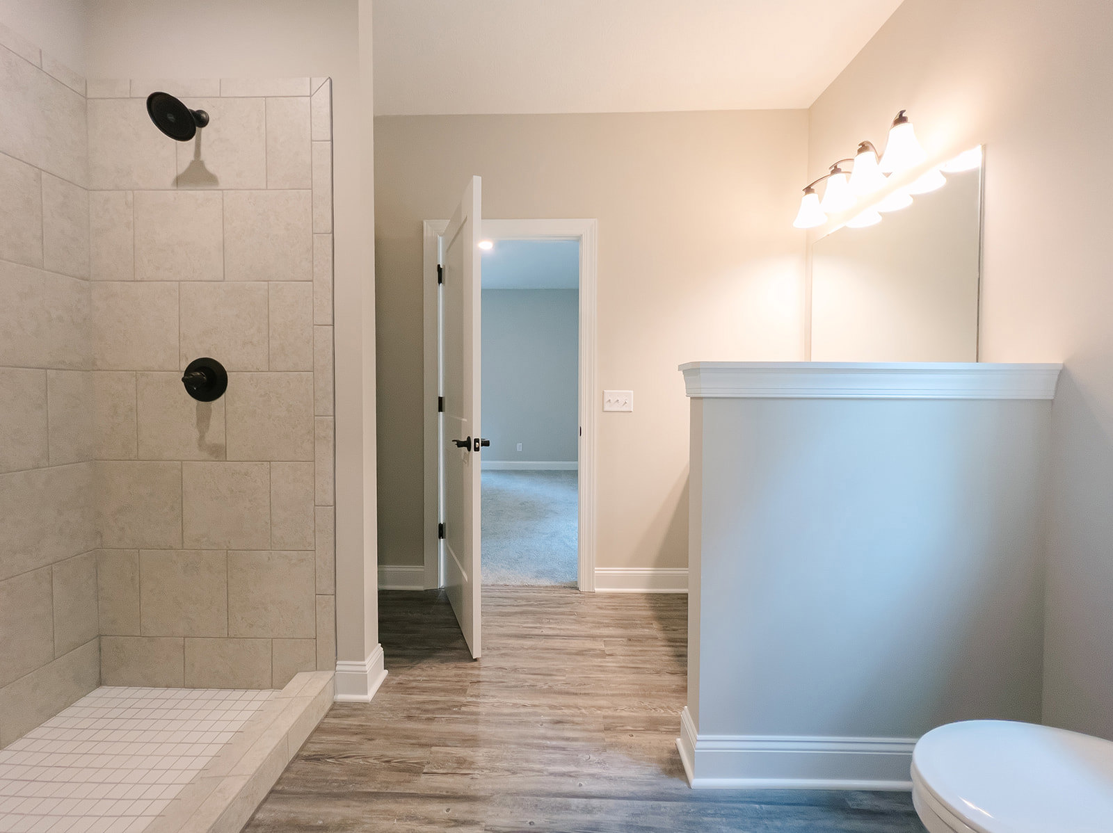 Modern bathroom featuring a glass-enclosed shower, white toilet with closed lid, chrome faucet, white tile floor with black grout lines, and an open door leading to an adjacent