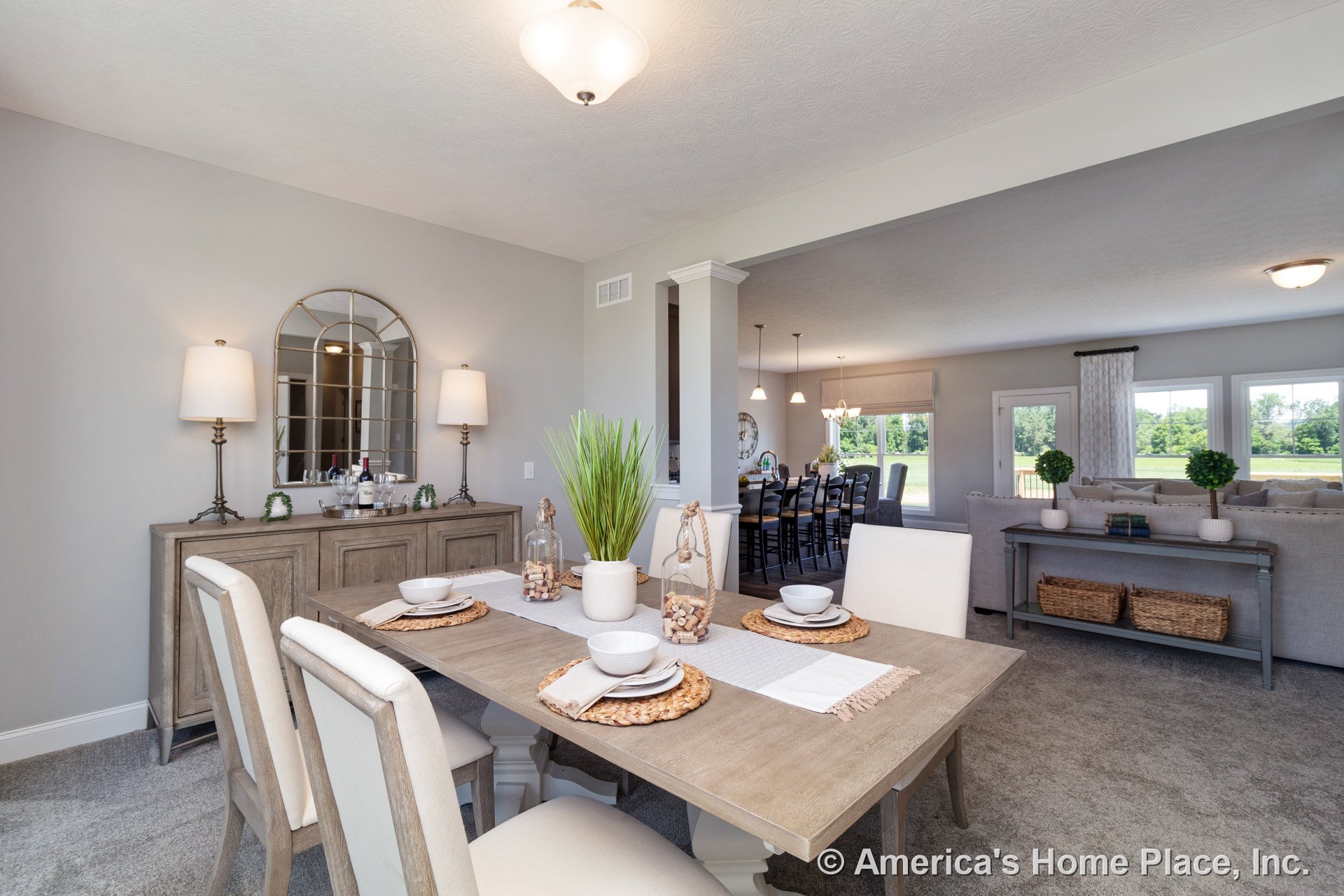 Open concept dining and living area with carpeted floors, multiple built-in ceiling lights, large windows with decorative trim, neutral wall paint, and baseboard trim; dining space