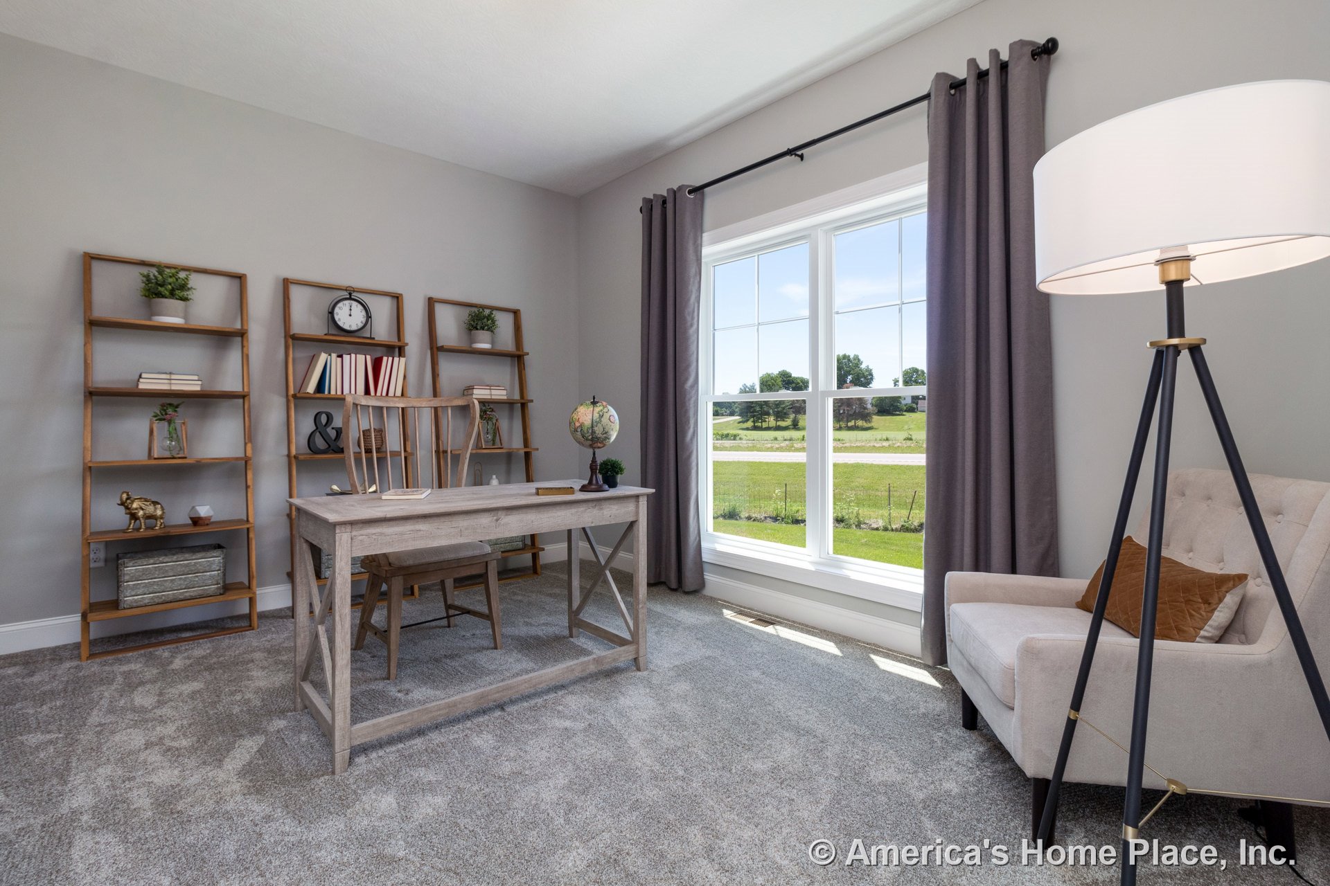 Home office with built-in shelving units, large double-pane windows framed by white trim and gray curtains, gray carpet flooring, neutral wall paint, and a smooth-finish ceiling.