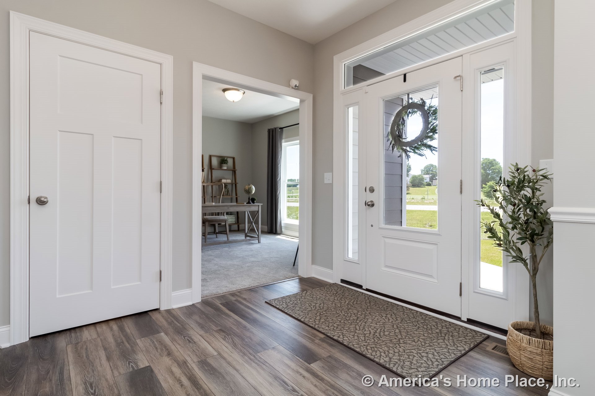 White front door with glass sidelights and transom window, wood-look vinyl plank flooring, gray painted walls, white trim and baseboards, ceiling light fixture, office room visible