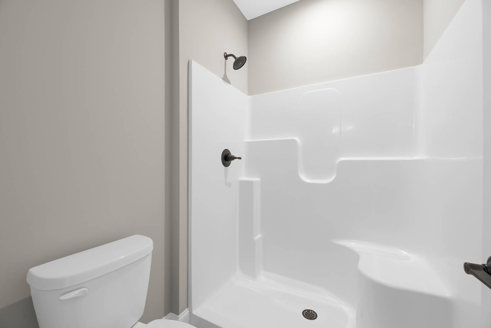 Modern bathroom with white tile walls, glass-enclosed shower featuring chrome showerhead, and sleek white toilet