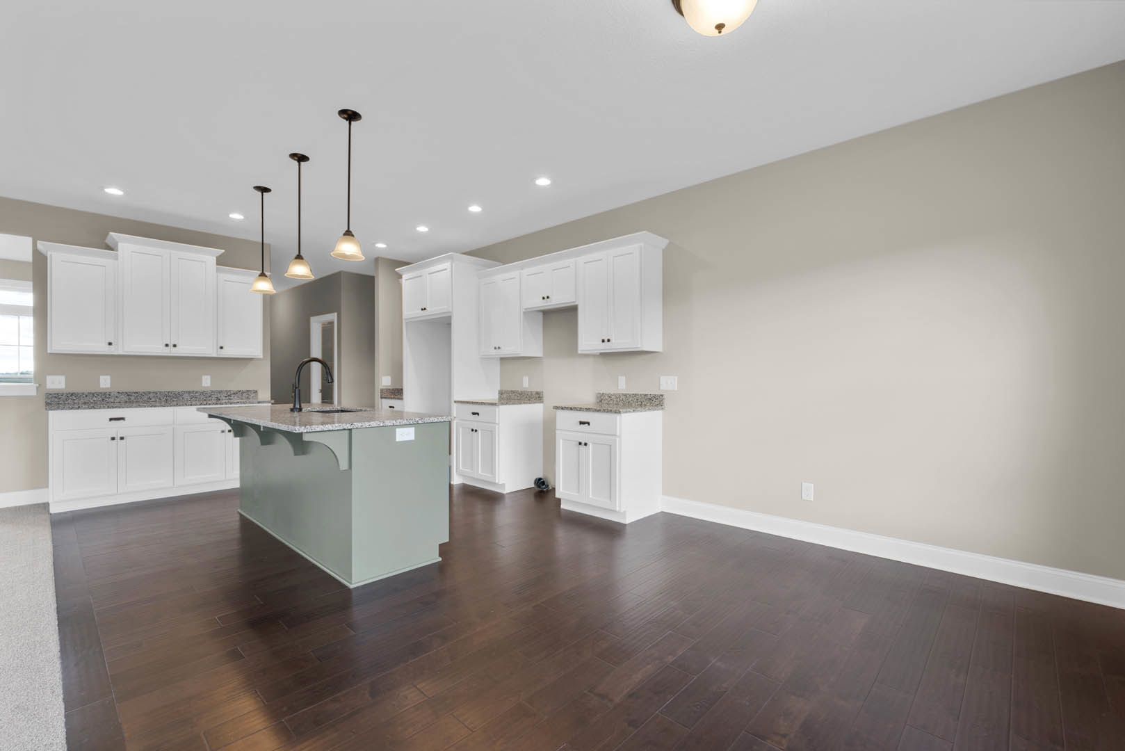 Kitchen with marble-topped island, dark wood flooring, white cabinetry and trim, pendant light fixture illuminated, window with white shade, black-bordered white surfaces