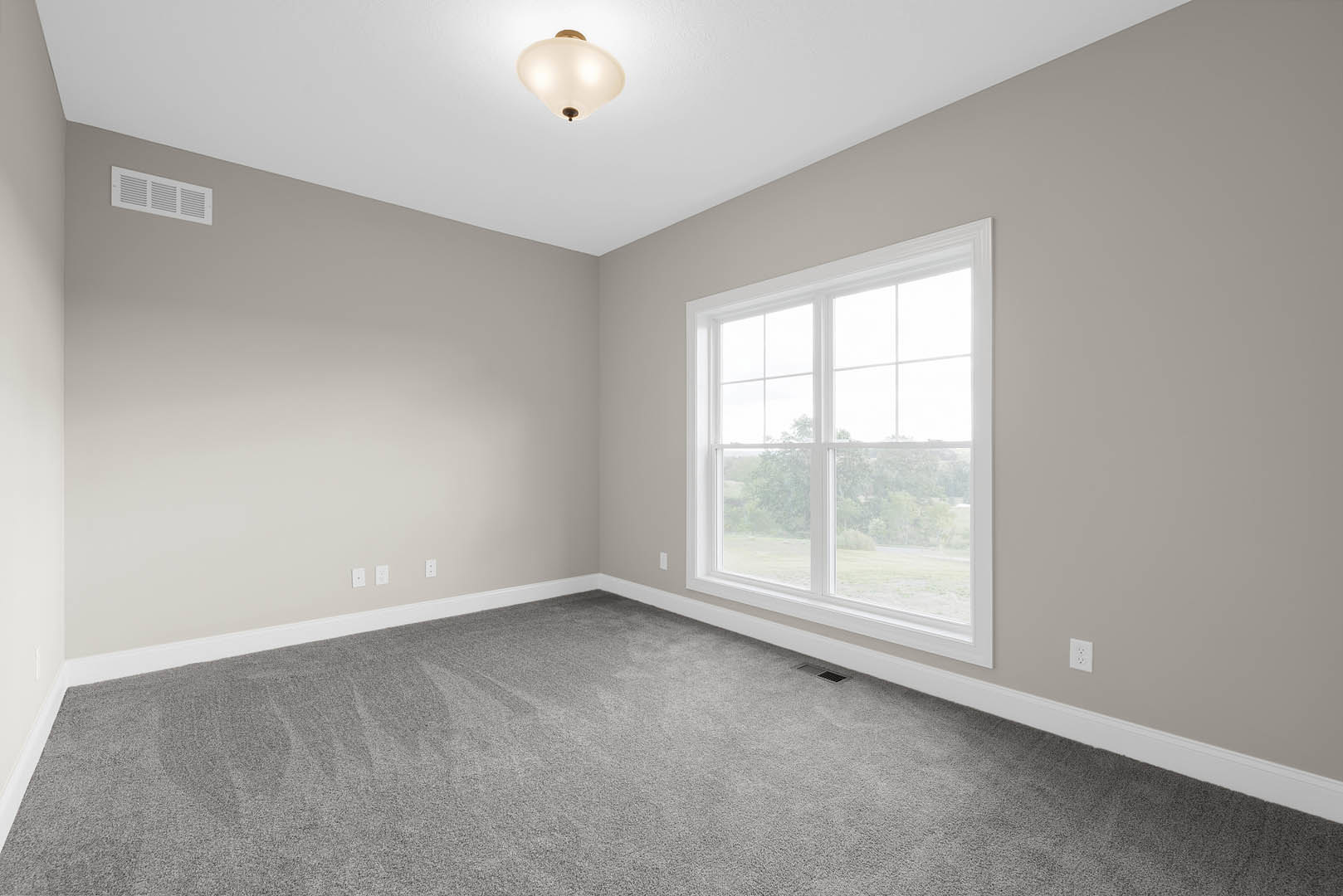 Bedroom with grey carpet, white walls, large window showing trees outside, wall vent, and modern ceiling light fixture