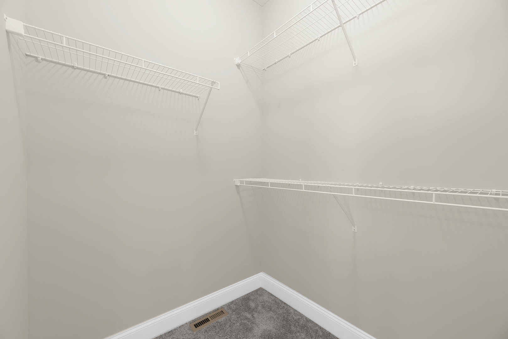 White built-in shelves with metal bars on a plaster wall in a bright room