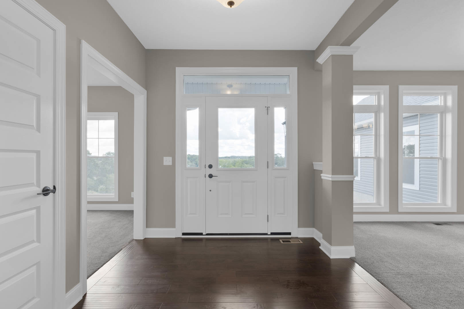 Hallway with dark wood laminate flooring, white paneled door featuring glass panes, white baseboard molding, and neutral walls
