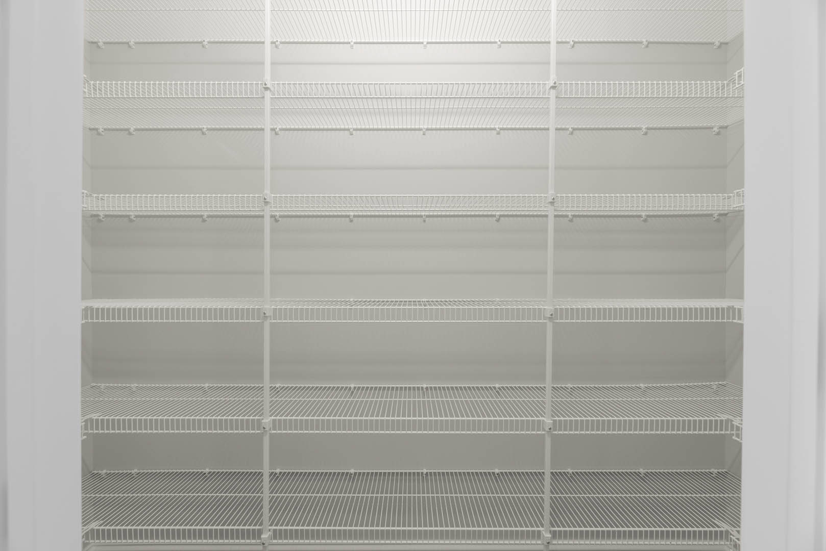 White built-in shelving unit against a white wall in a bright room with window blinds.