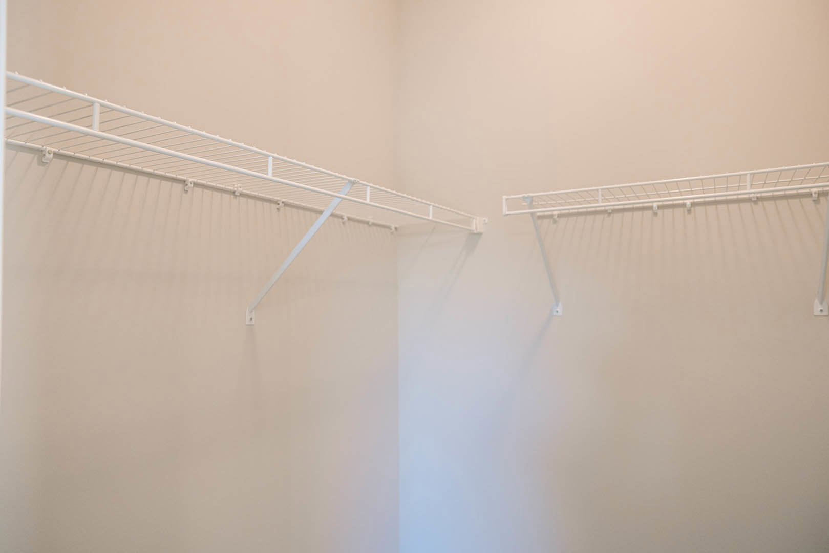 Two white wall-mounted shelves with a white metal rod and blue stripe in a minimalist room with light-colored walls