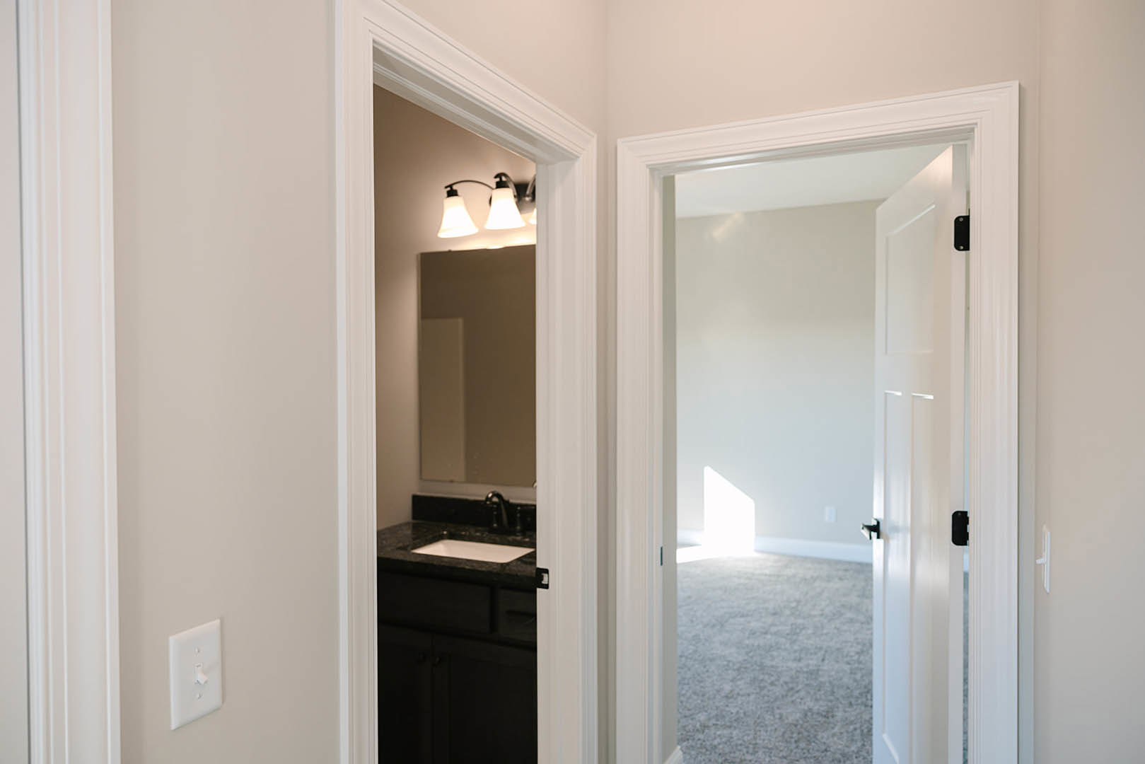 White bathroom with rectangular mirror above a modern sink, chrome faucet, white cabinetry, and smooth plaster walls.