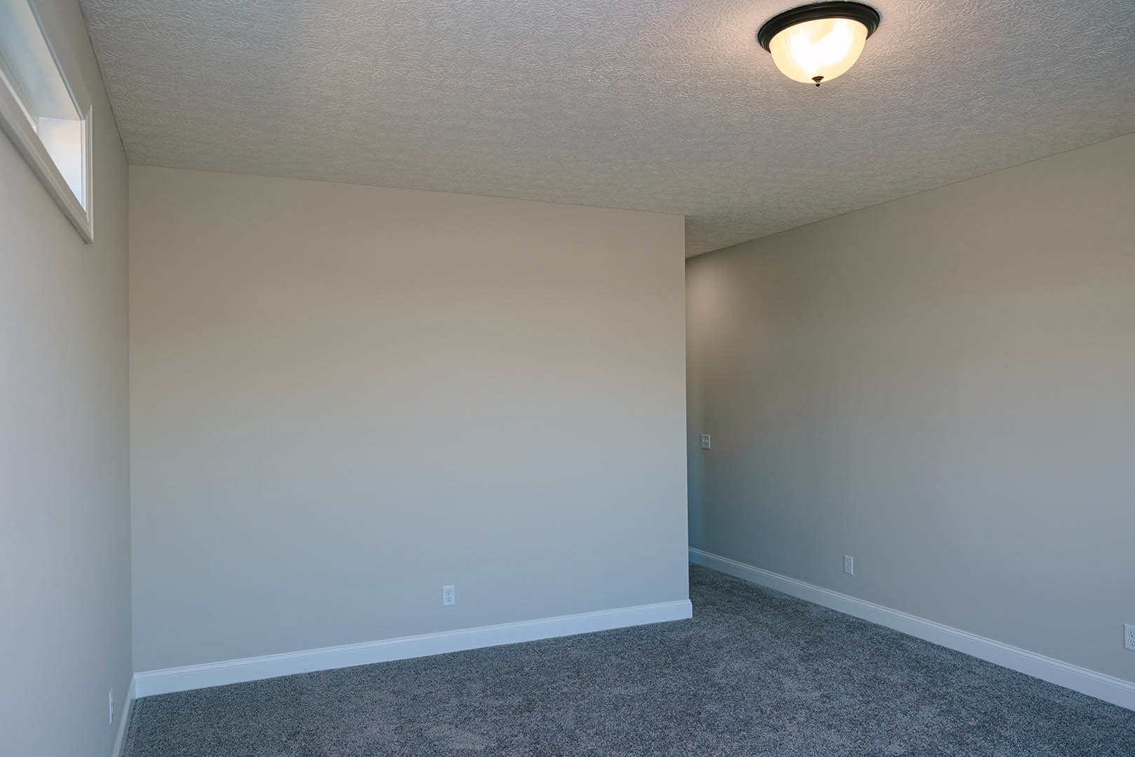 Modern living space with white plaster walls, ceiling molding, recessed lighting fixture, large window, and neutral carpet flooring